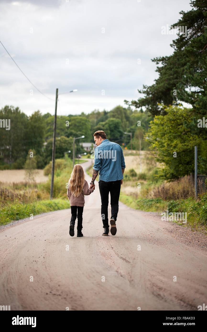 Finlandia, Uusimaa, Raasepori, Karjaa, Padre caminando con su hija (6-7) a lo largo de country road Foto de stock