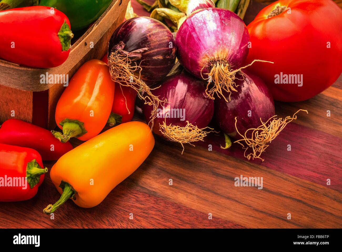 Bellos y coloridos de antioxidantes. Rojo, amarillo, naranja y violeta de los pimientos con cebolla y tomate. Foto de stock