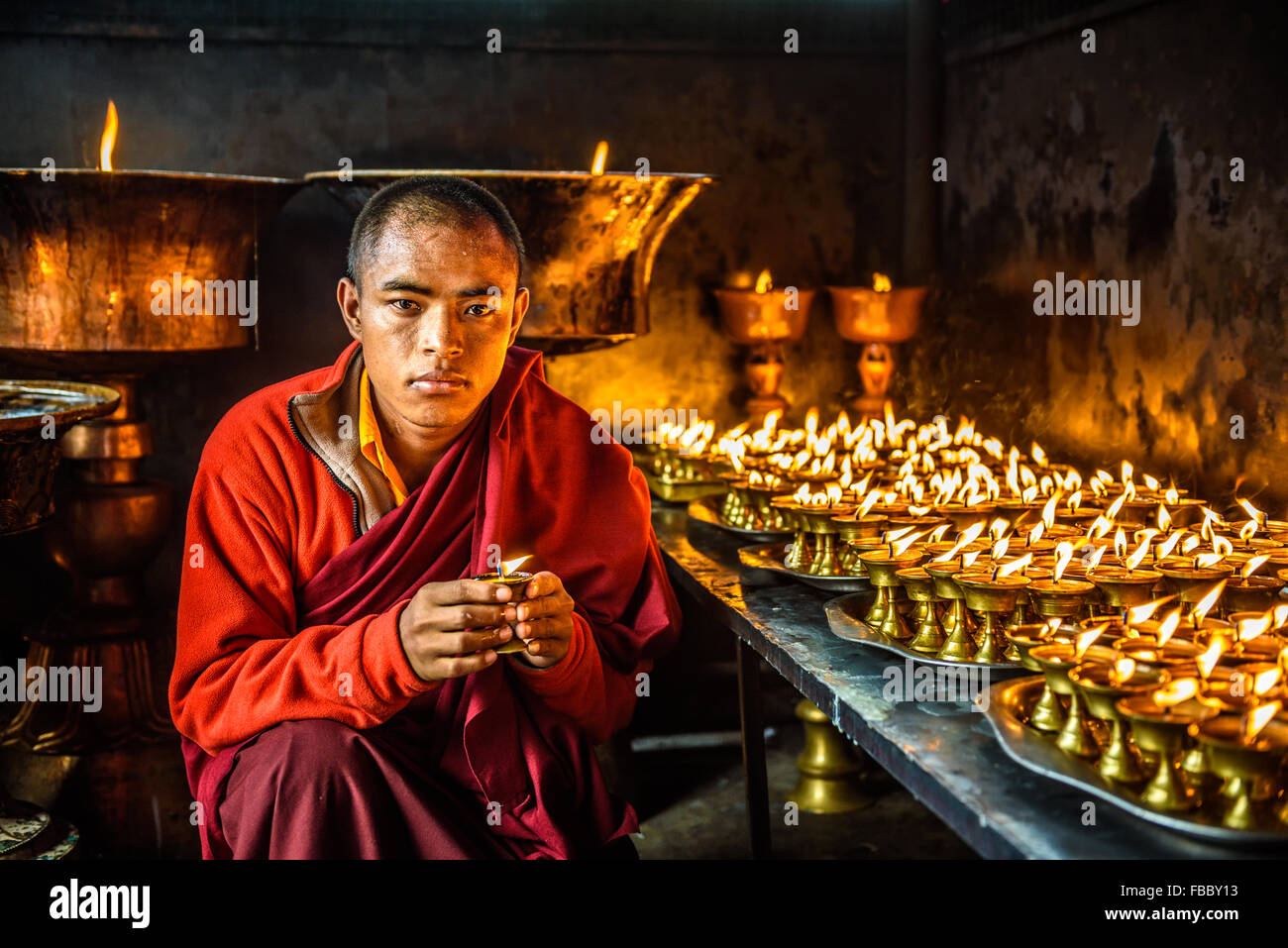 Monje budista hasta la iluminación a la luz de las velas en el interior de un templo budista en Katmandú. Foto de stock