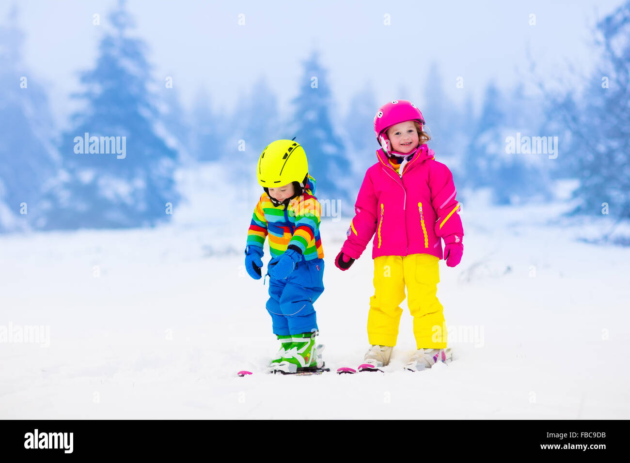 Los niños de esquí en las montañas. Niños Niño en un colorido traje y casco de seguridad aprendiendo a esquiar. Deportes de invierno para la familia Foto de stock