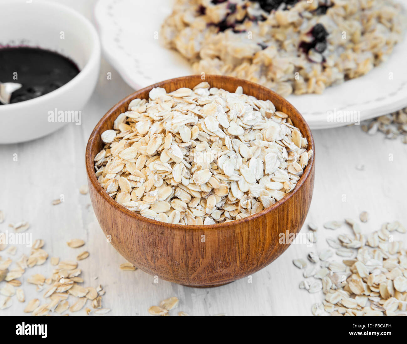 La harina de avena en un recipiente de madera y gachas en el fondo Foto de stock