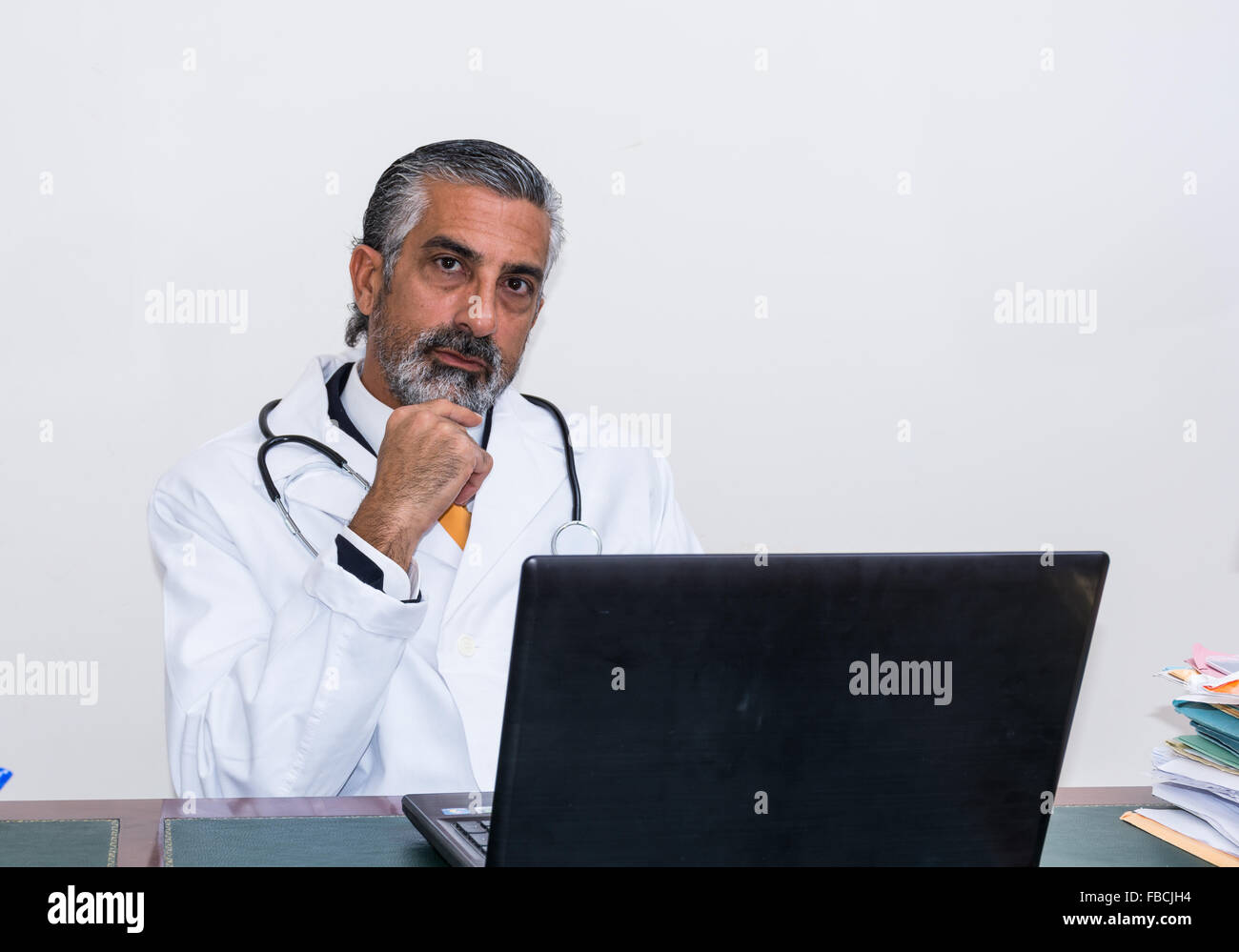 El doctor usa el portátil en su estudio. Incluso médicos y medicamentos, al igual que otros profesionales, utilizar las nuevas tecnologías, como un ordenador portátil. Foto de stock
