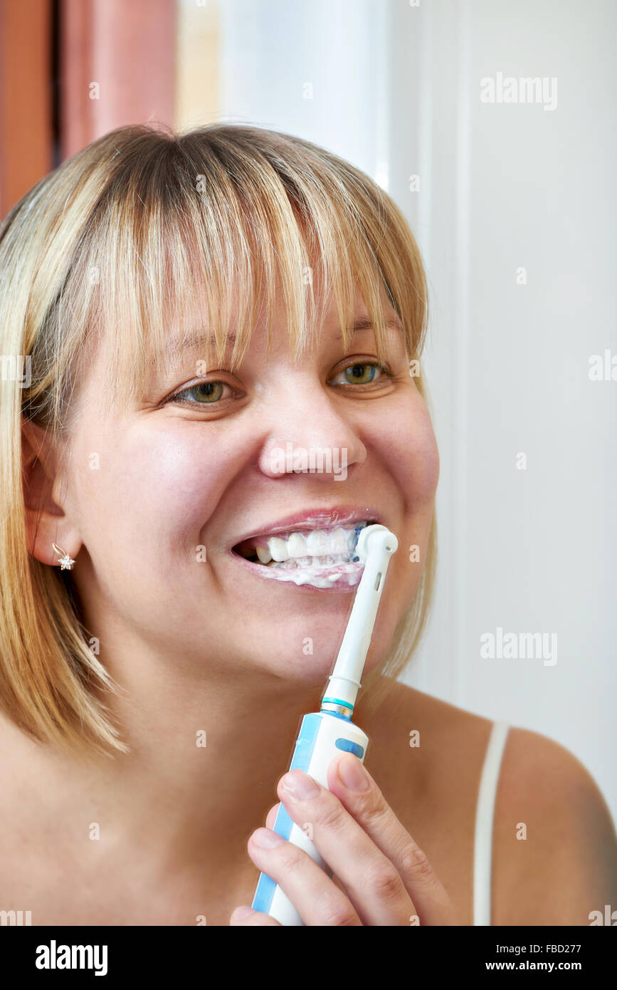 Mujer cepillarse los dientes cerca de espejo Foto de stock