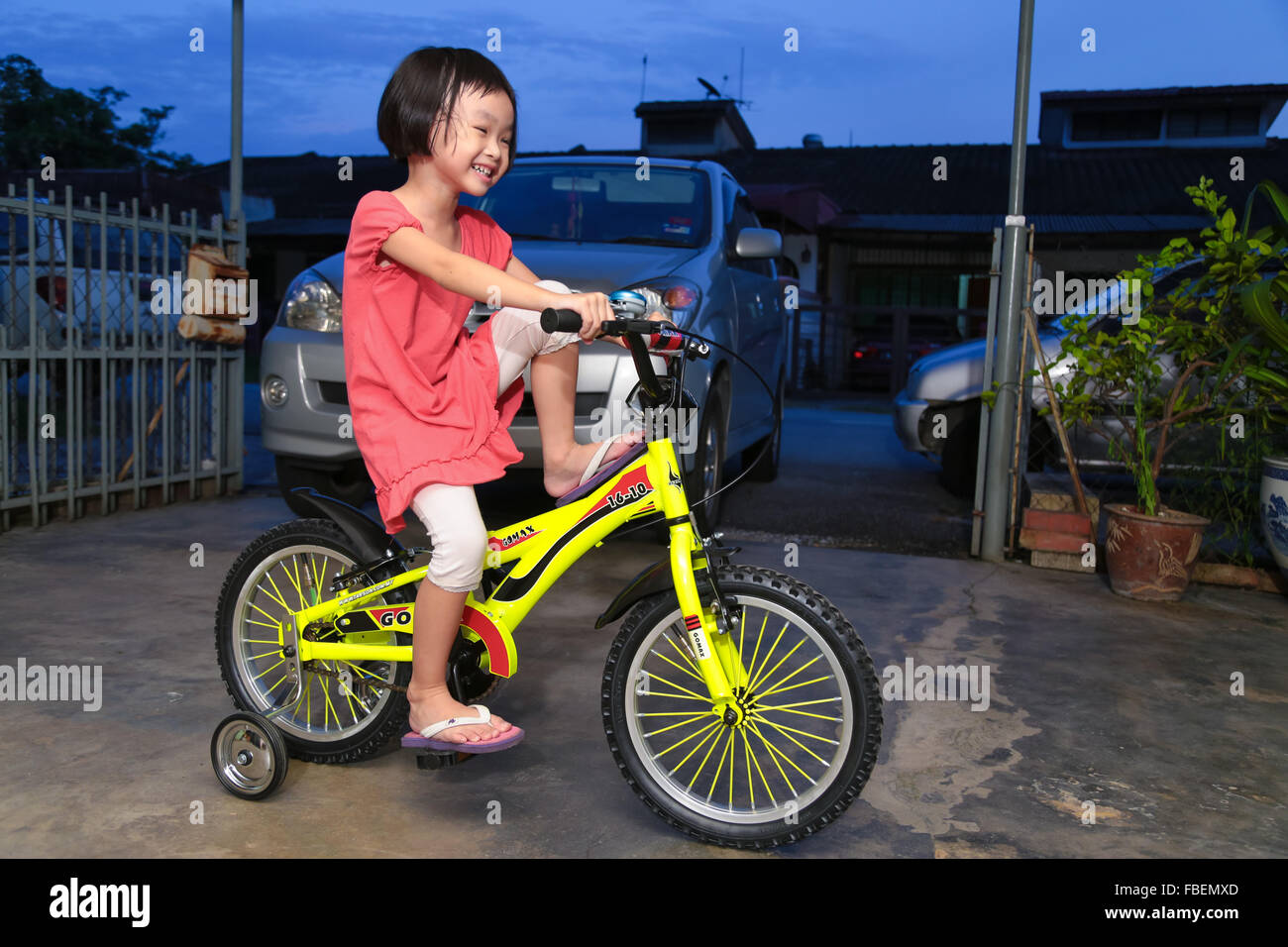 Feliz, la niña aprender a montar en bicicleta a su niño con ruedas  auxiliares Fotografía de stock - Alamy