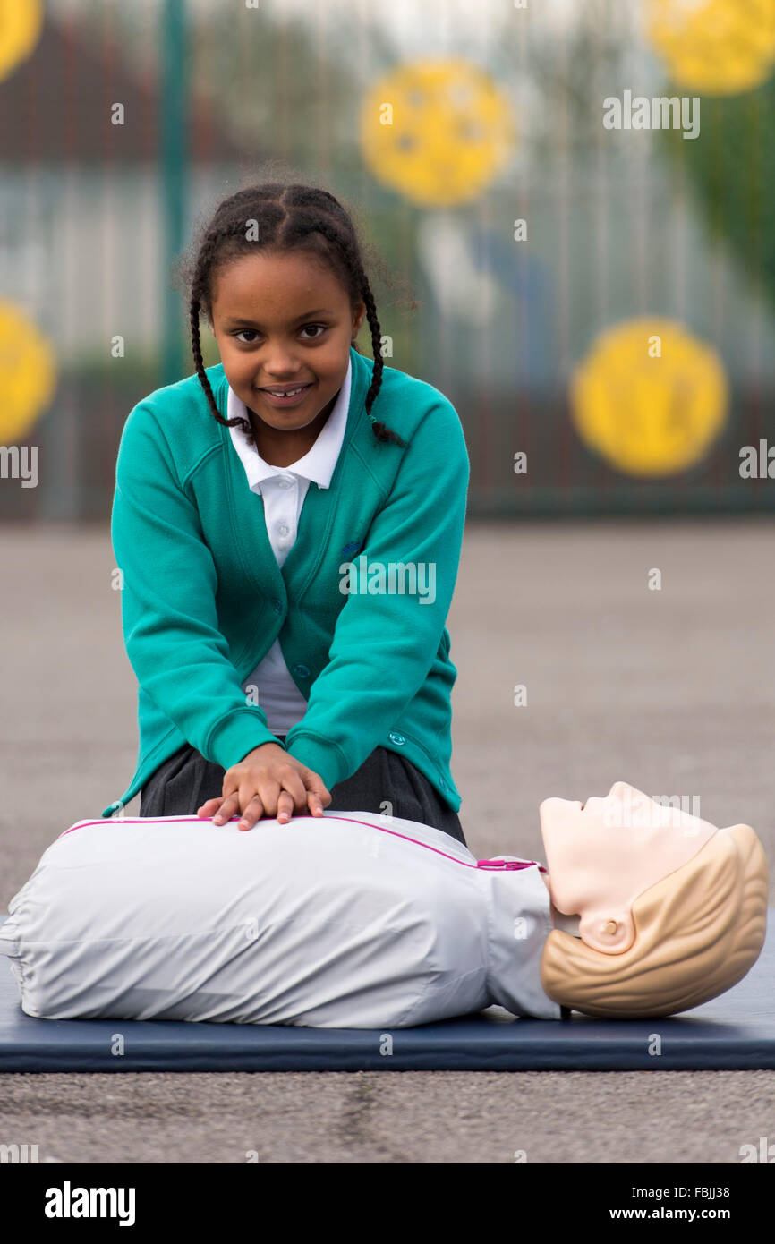 Una alumna aprende técnicas de primeros auxilios para salvar su vida practicando en un maniquí en la escuela. Foto de stock