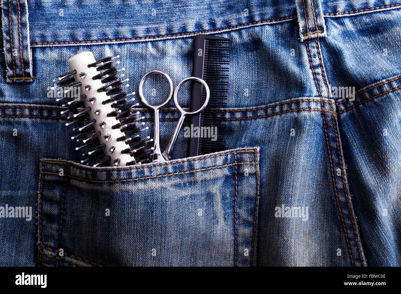Pincel, tijeras y peine en el bolsillo de los pantalones vaqueros Foto de stock