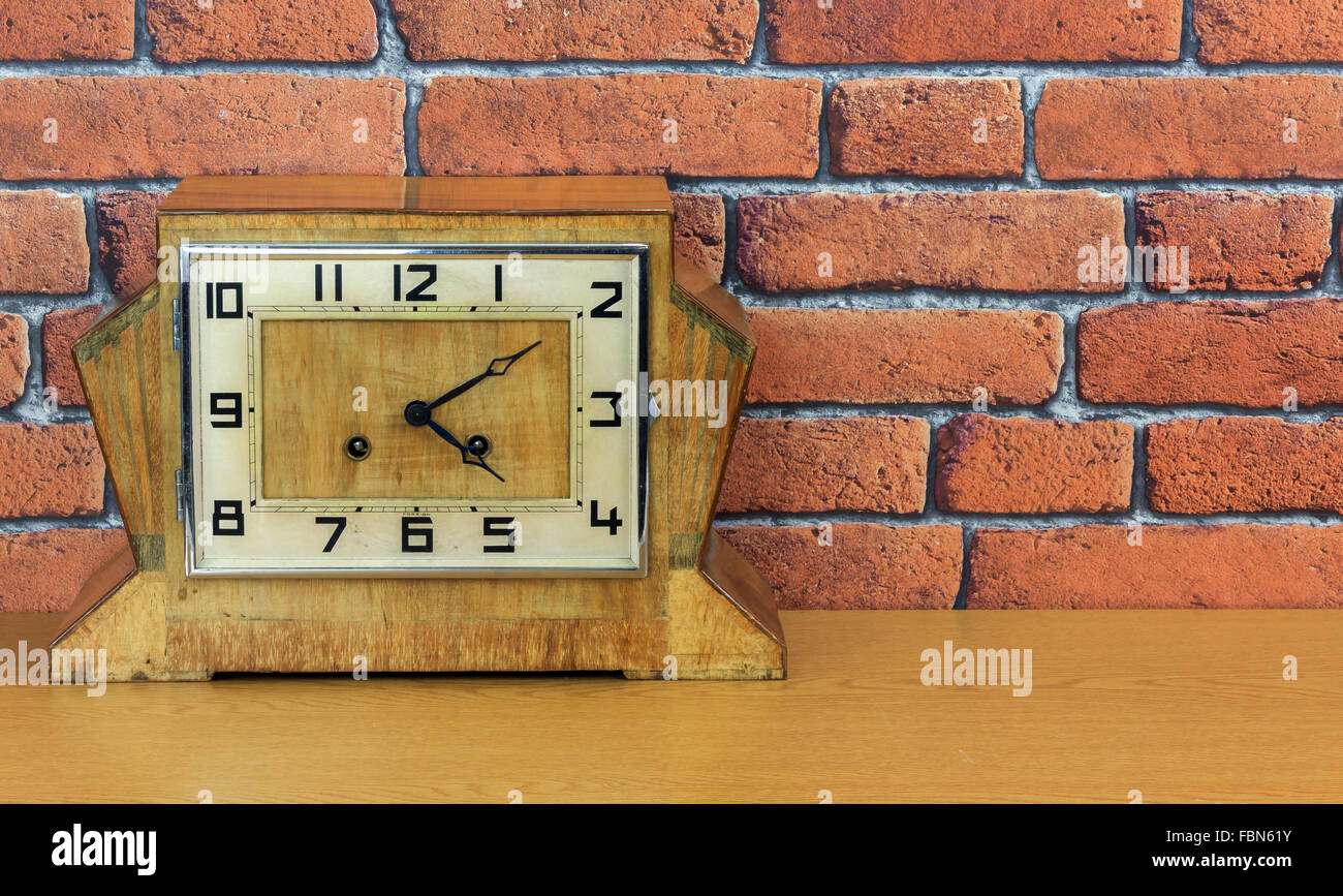Vintage art deco de mantel de madera con el viejo reloj de pared de ladrillo rojo fondo de efecto Foto de stock