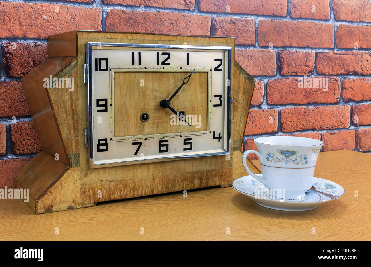 Vintage art deco de mantel de madera con el viejo reloj de pared de ladrillo rojo y fondo de efecto tazita y lleno con té Foto de stock