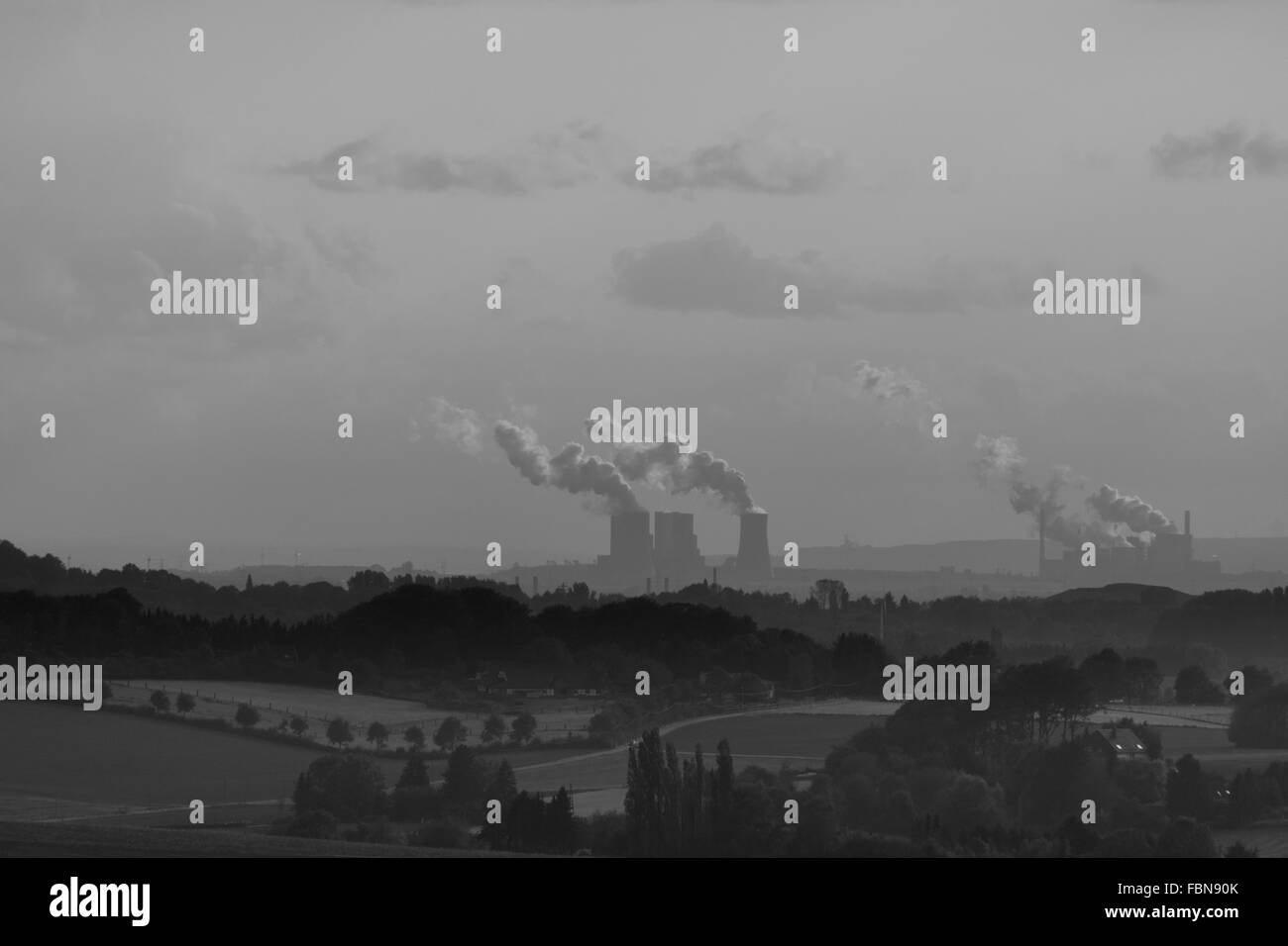 Distancia media vista de fábrica que emite humo contra el cielo Foto de stock