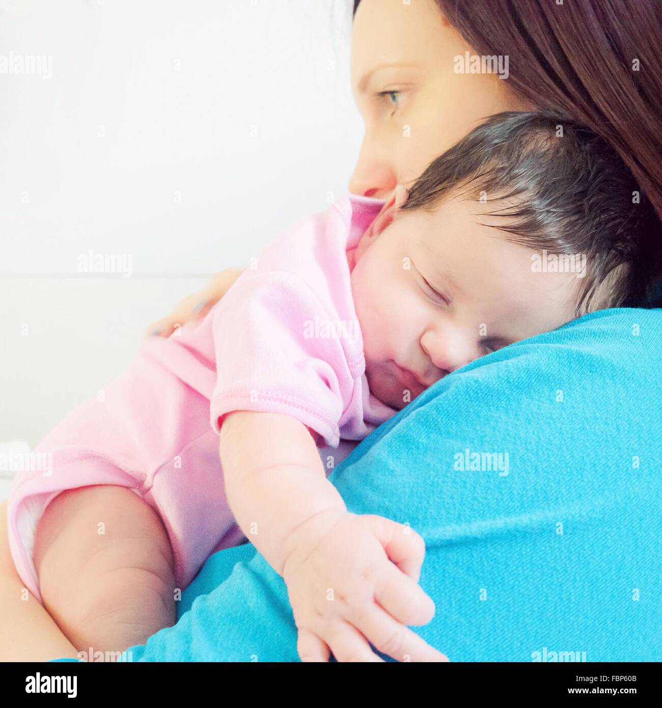 Vista lateral de la madre sosteniendo lindo bebé contra fondo blanco. Foto de stock
