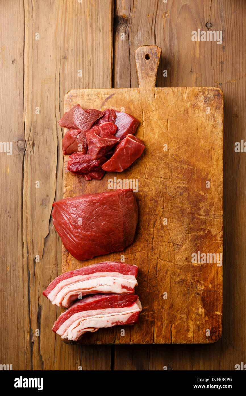 Los diferentes tipos de carne fresca cruda sobre una tabla de cortar el bloque de corte sobre fondo de madera Foto de stock