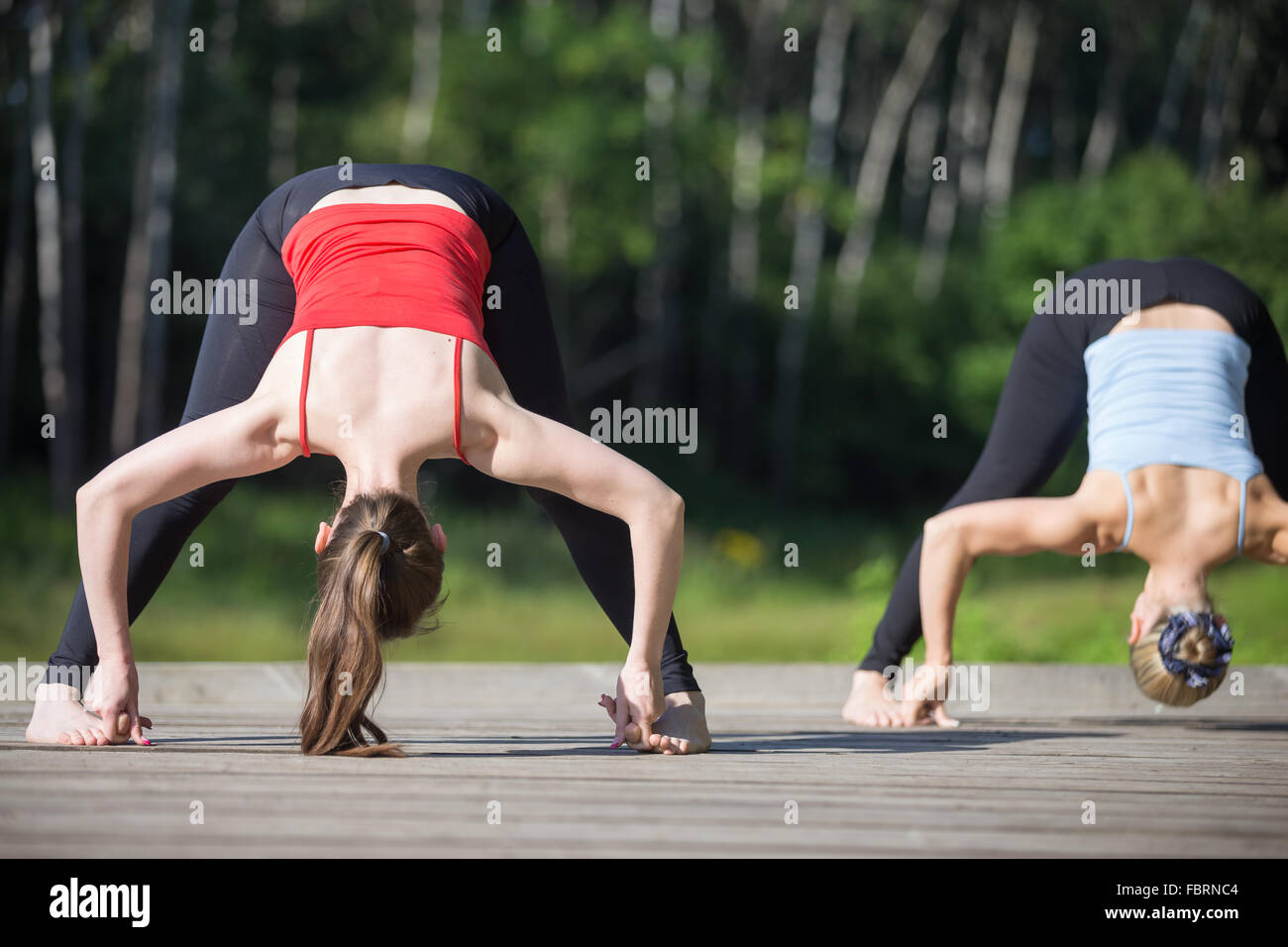 Colocar dos hermosas jóvenes mujeres vistiendo ropa deportiva camisetas  rojas y azules trabajando al aire libre en el parque el día de verano,  haciendo amplia Fotografía de stock - Alamy