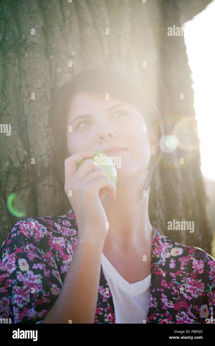 Mujer sosteniendo apple, mirando dreamily, Retrato Foto de stock