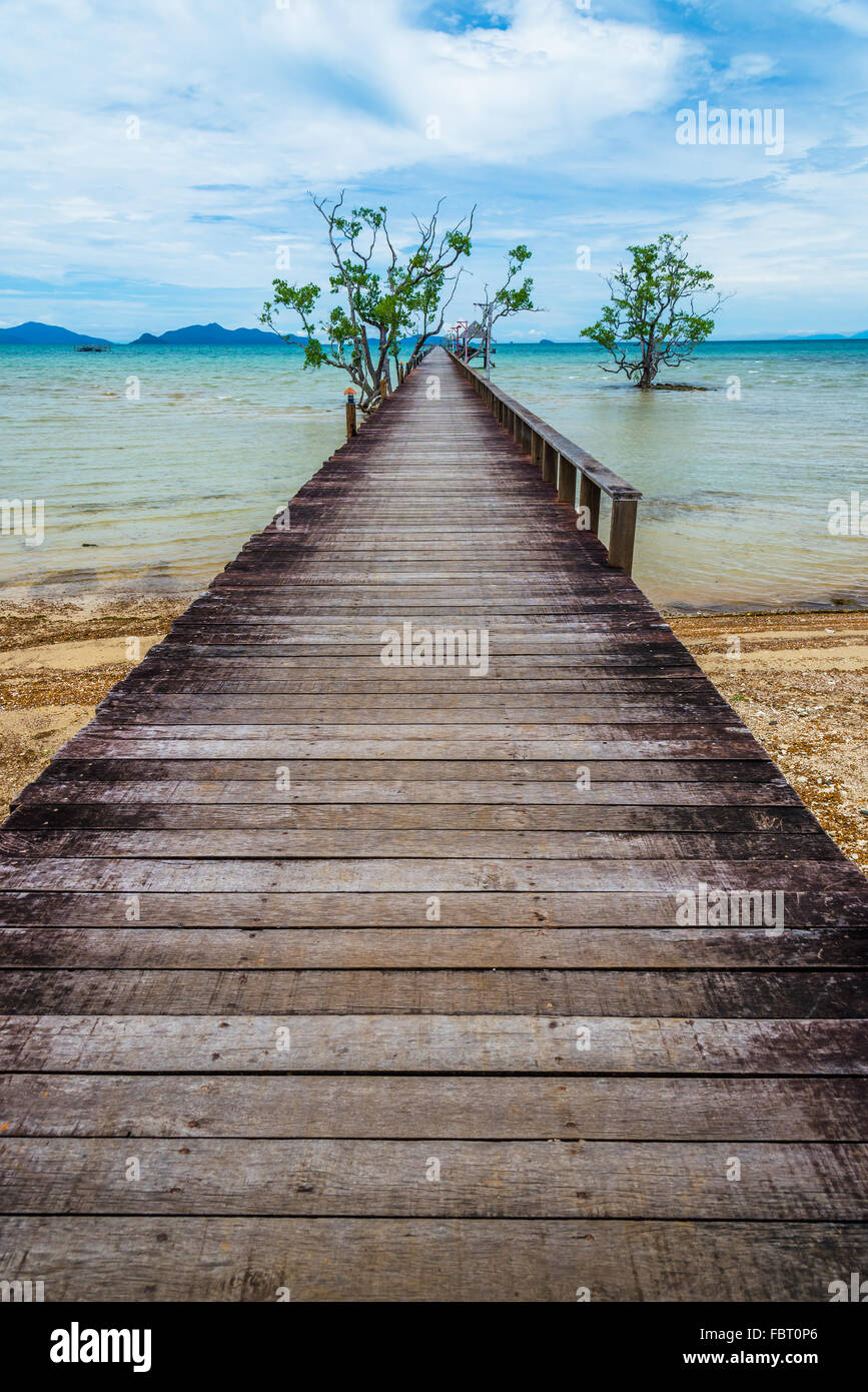 Largo puente de madera sobre la playa, en la isla Kohmak, Tailandia Foto de stock
