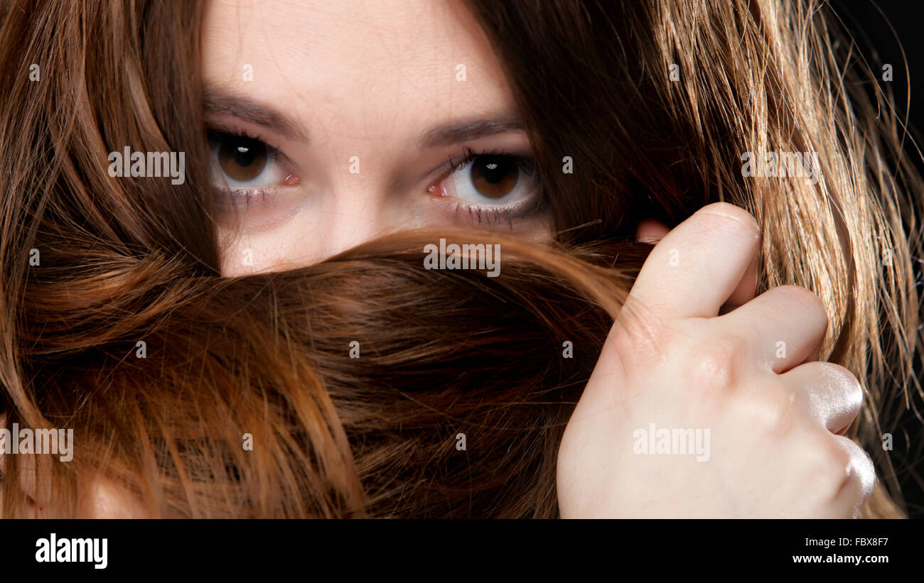 Closeup mujer cubre el rostro por largos pelos marrones Foto de stock
