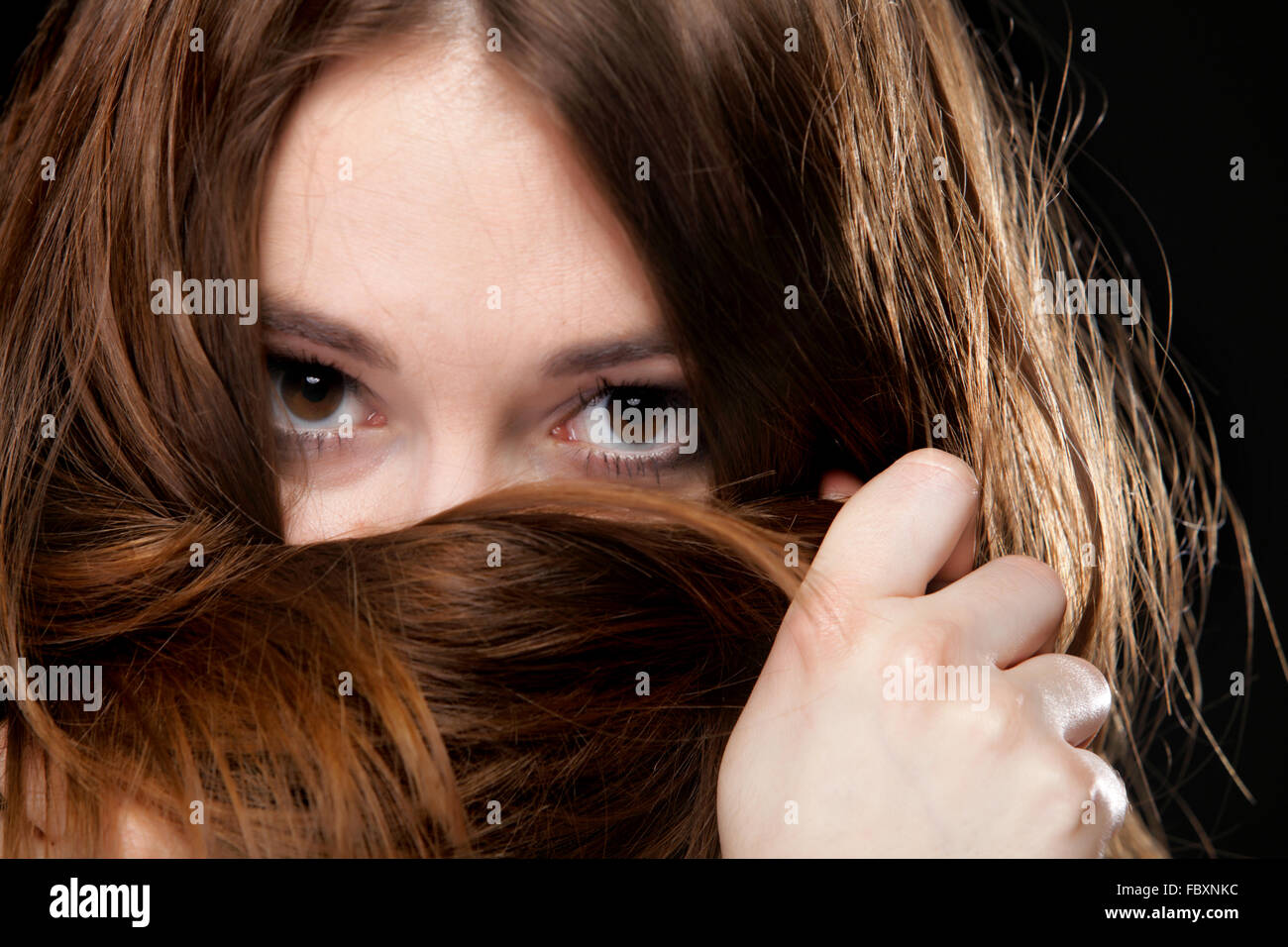 Closeup mujer cubre el rostro por largos pelos marrones Foto de stock