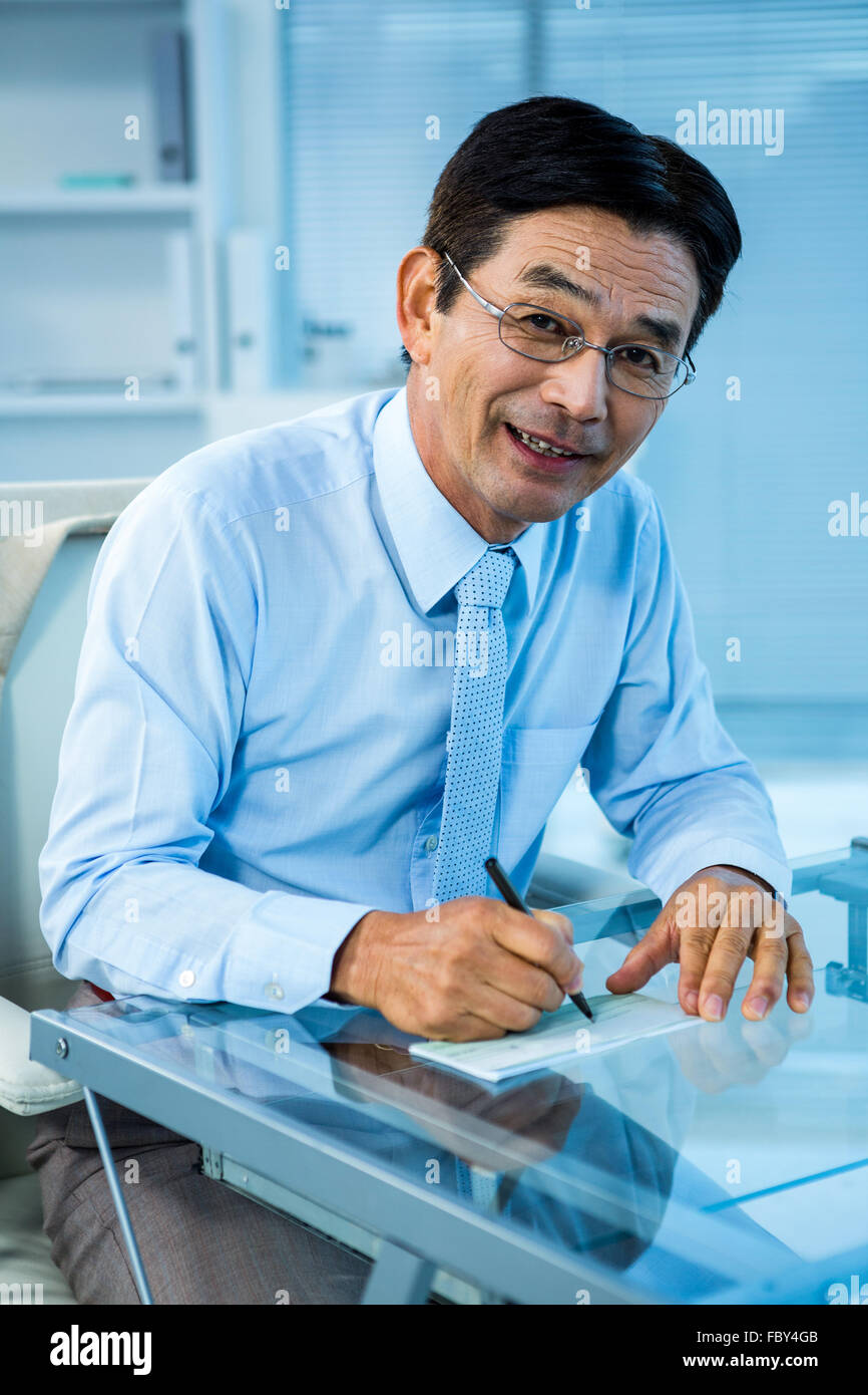 Sonriente empresario asiático firma el documento Foto de stock
