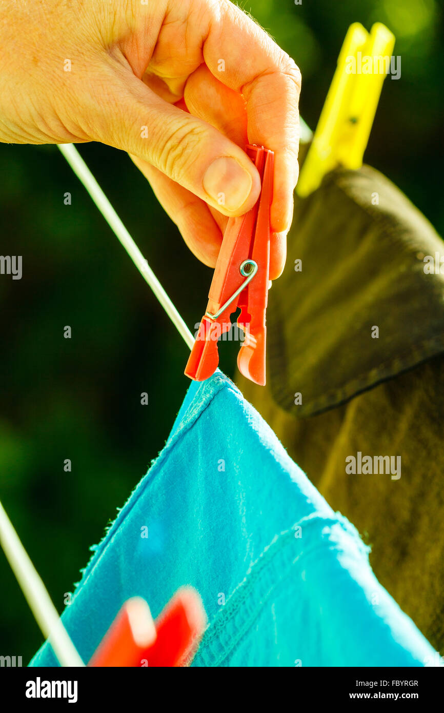 Mujer mano colgando ropa húmeda en línea de cuerda Foto de stock