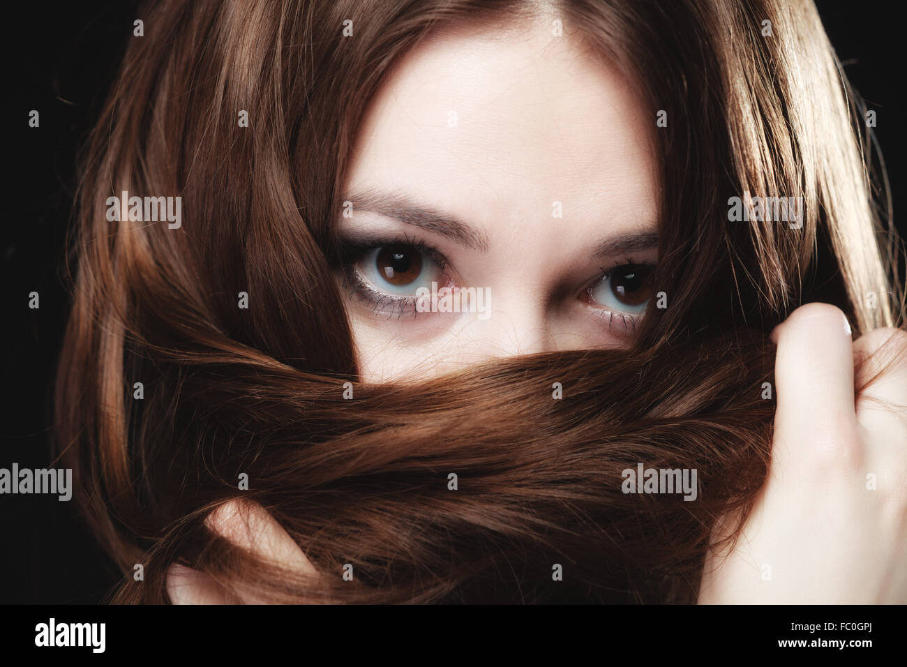 Mujer cubre el rostro por largos pelos marrones Foto de stock