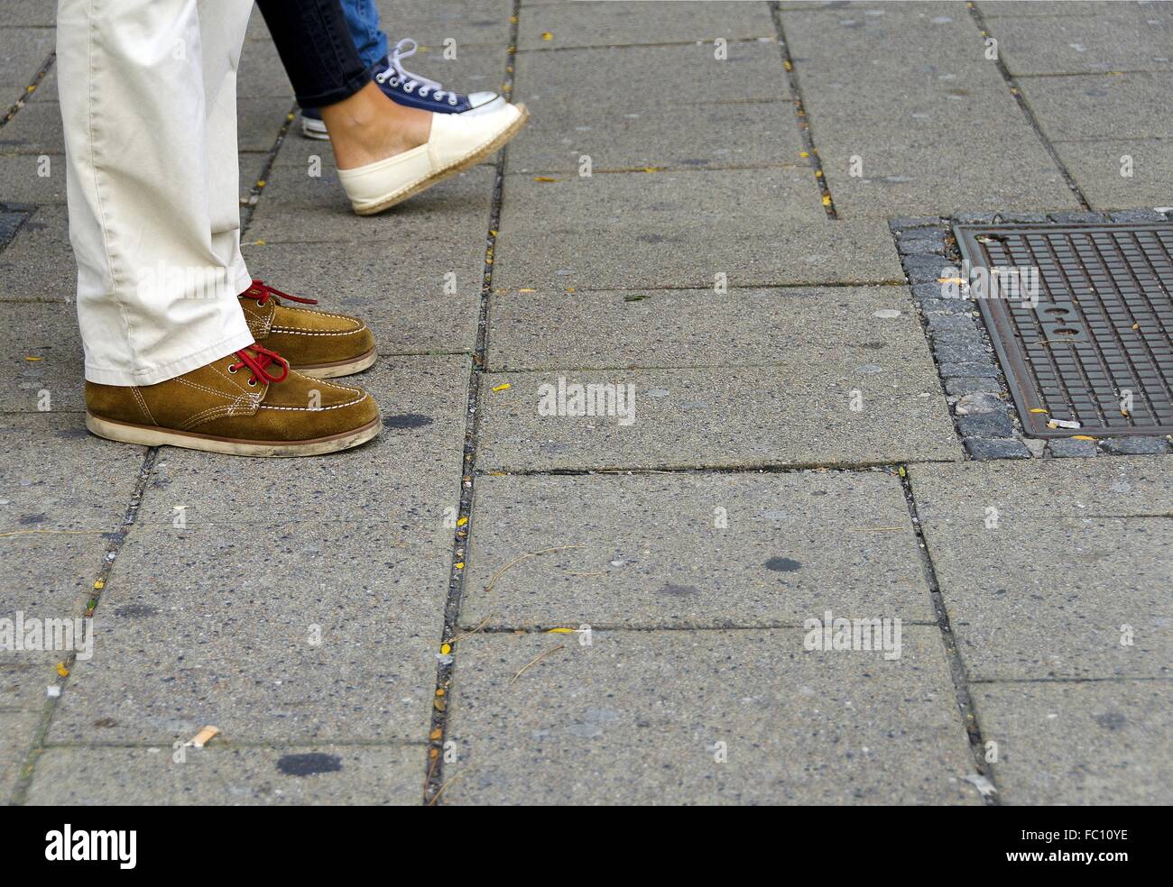 Pies de compradores en una acera pavimentada Foto de stock