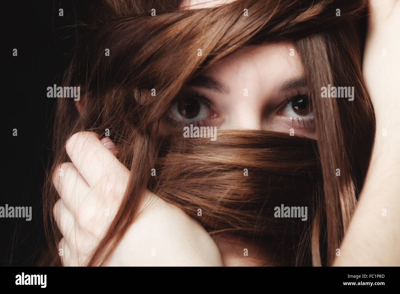 Mujer cubre el rostro por largos pelos marrones Foto de stock