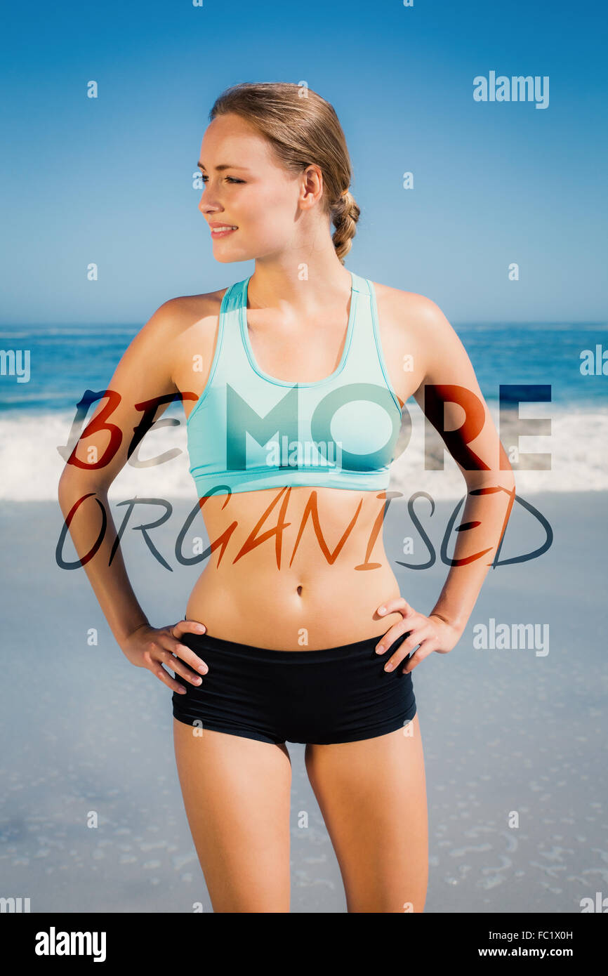 Imagen compuesta de montar mujer de pie en la playa con las manos en las caderas Foto de stock