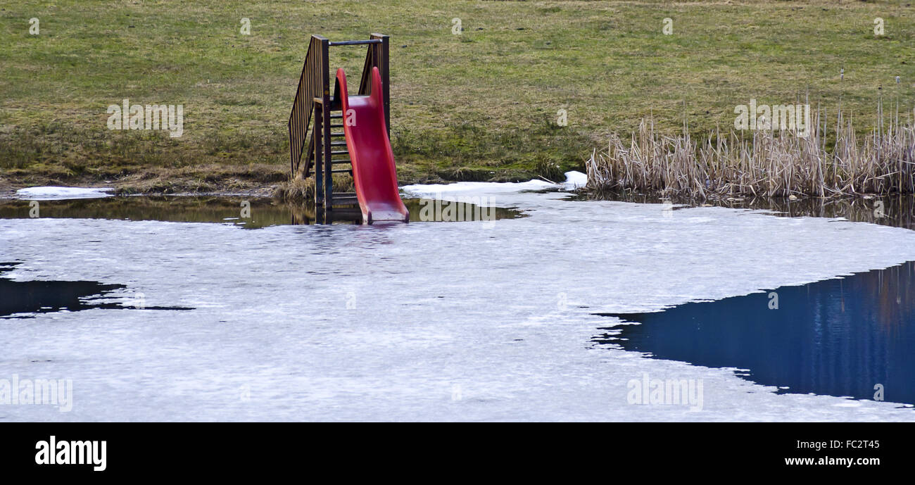 Tobogán de agua roja en un estanque icebound parcialmente Foto de stock