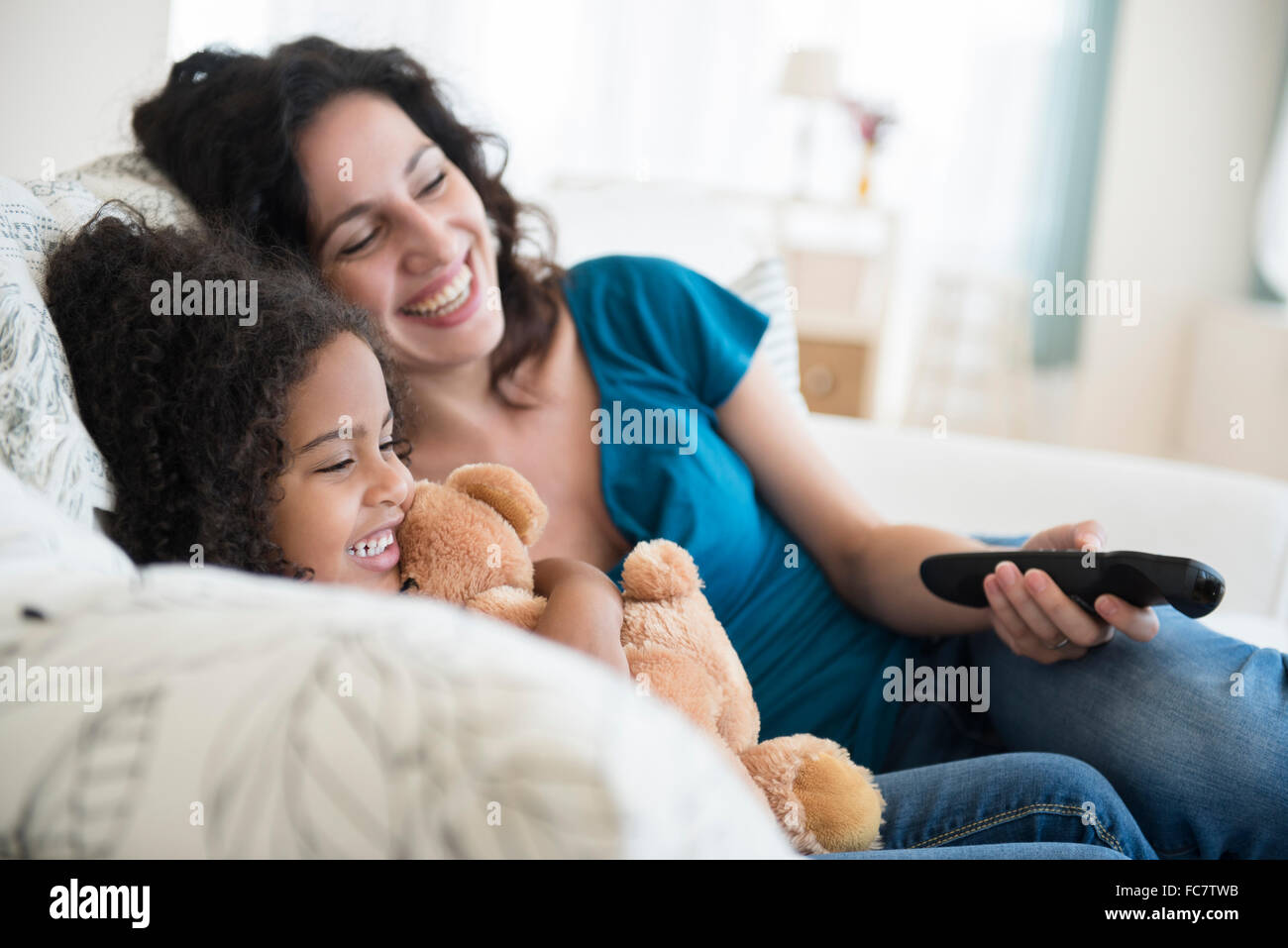 Madre e hija en el sofá viendo la televisión Foto de stock