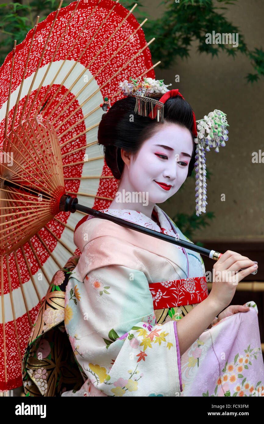 Retrato de sonriente geisha en batas floral con sombrilla roja en verano, Kyoto, Japón, Asia Foto de stock