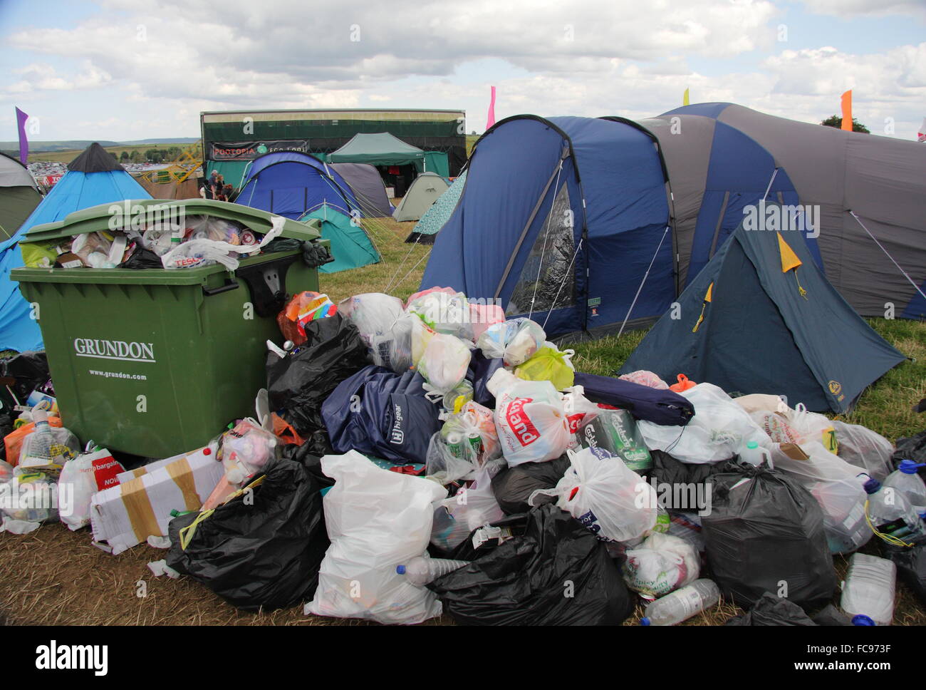 La basura rodea un bin por los asistentes al festival' tiendas de campaña en un camping en el campo y no festival de música en el Peak District, REINO UNIDO Foto de stock