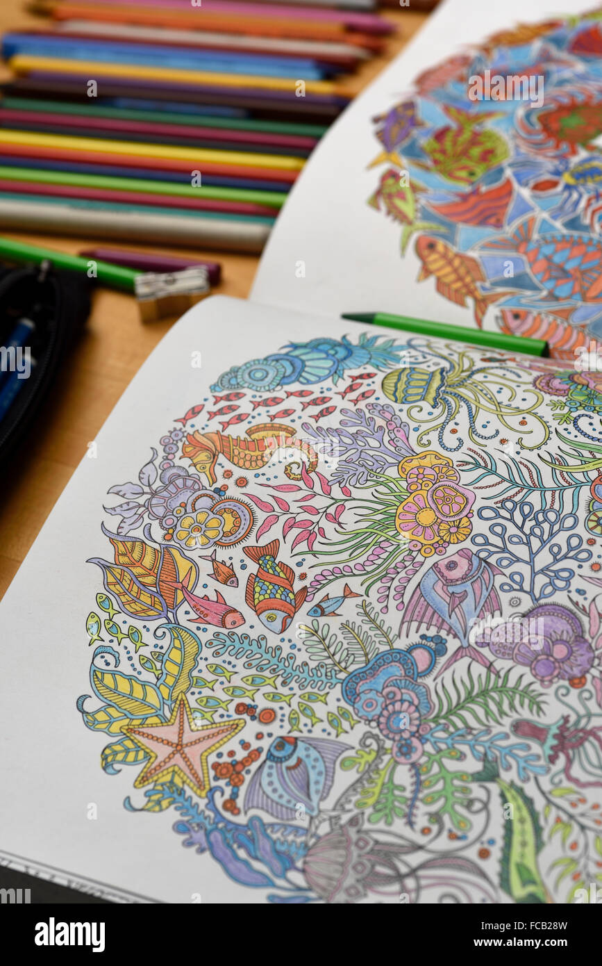 Libro para colorear de adultos en la mesa con lápices de colores Foto de stock