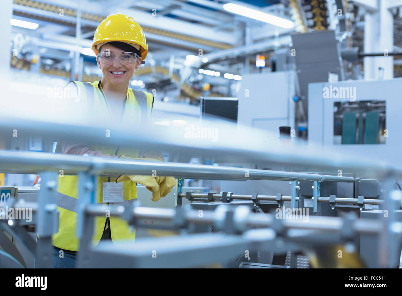 Retrato sonriente trabajadora en la maquinaria en la fábrica. Foto de stock