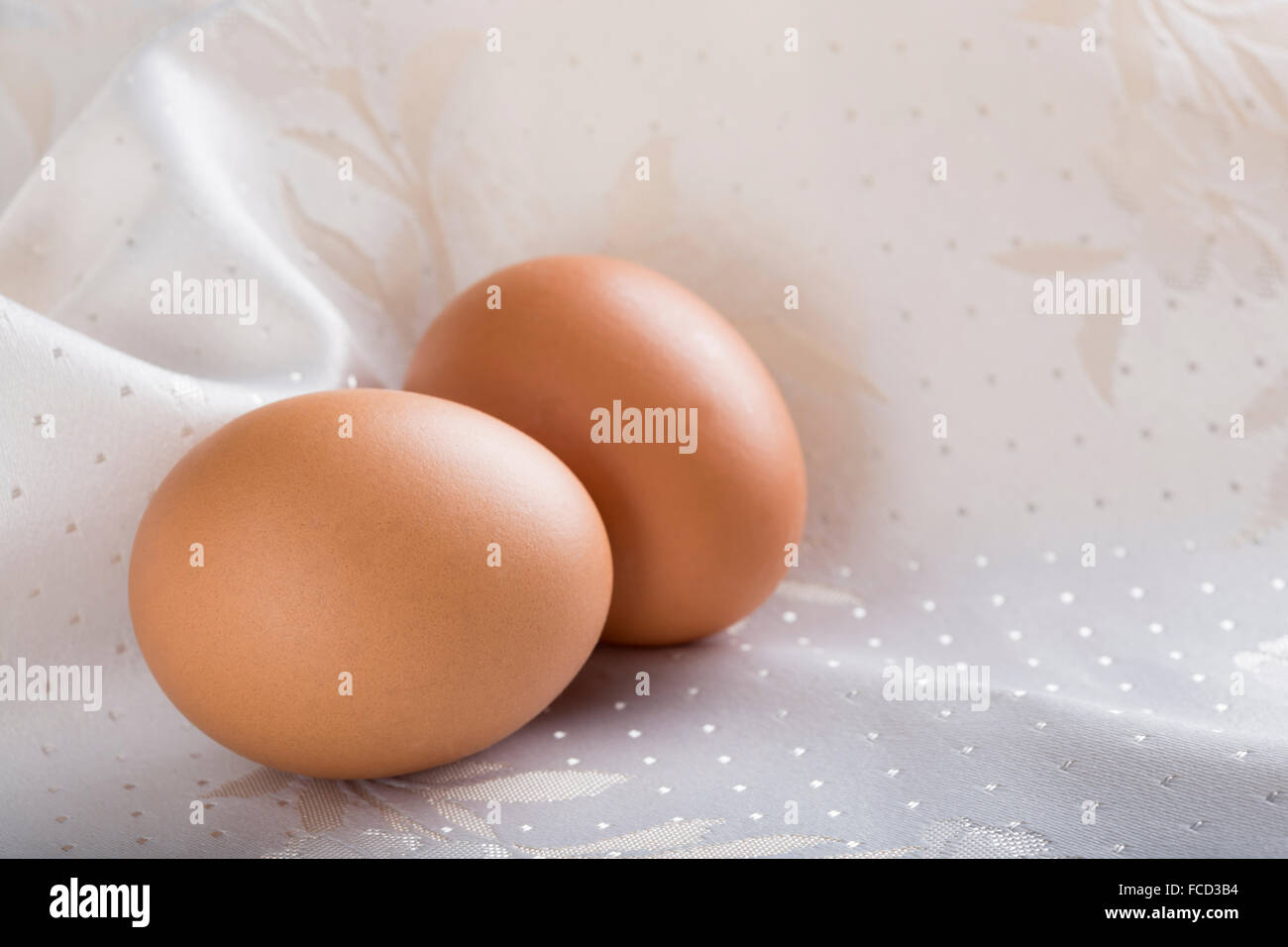 Dos huevos de color beige sobre fondo de seda Foto de stock