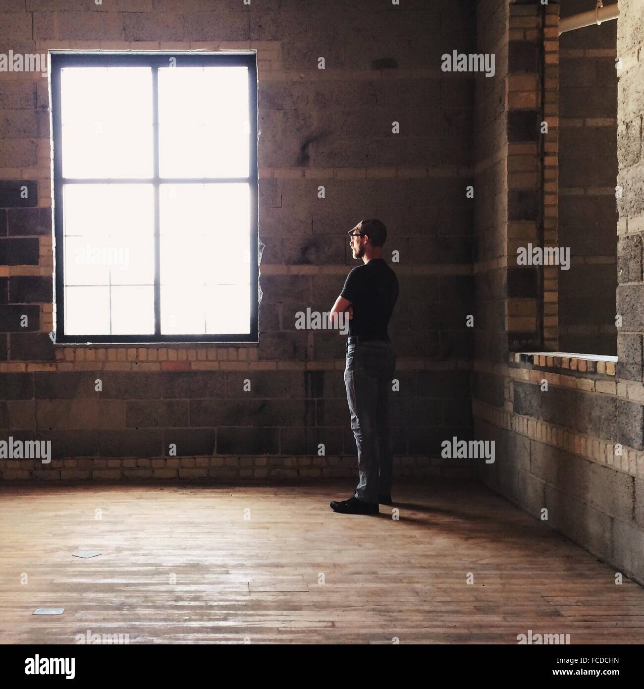 El perfil lateral de un hombre mirando hacia afuera de la ventana Foto de stock