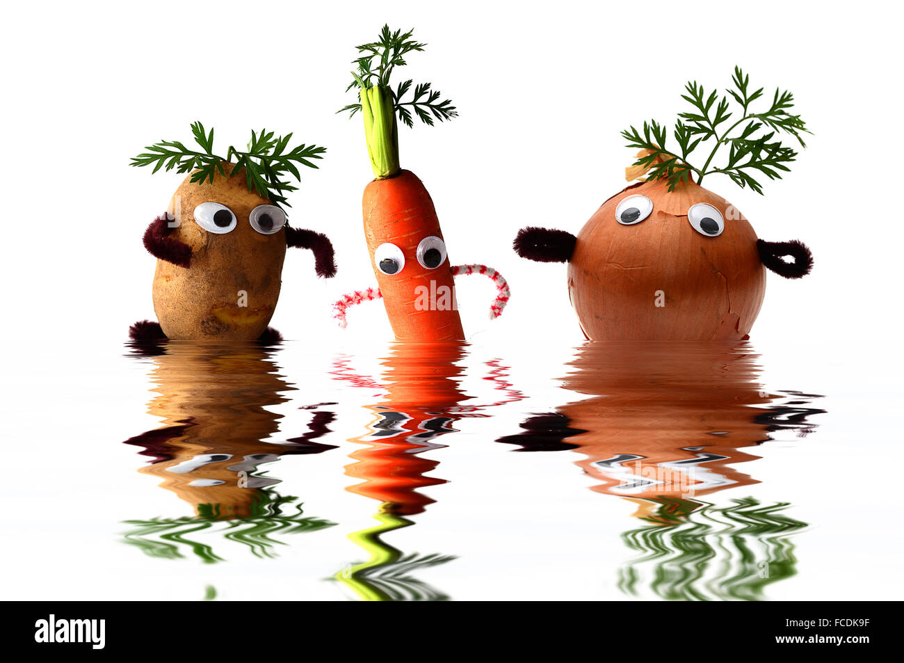 Patata, zanahoria y cebolla en agua con caras, imagen simbólica para comer sano Foto de stock