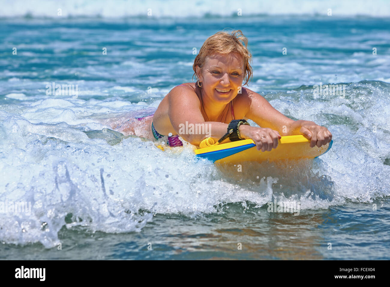 Alegre mujer de mediana edad - surfer con bodyboard surf la diversión en las pequeñas olas del mar Fotografía de stock Alamy