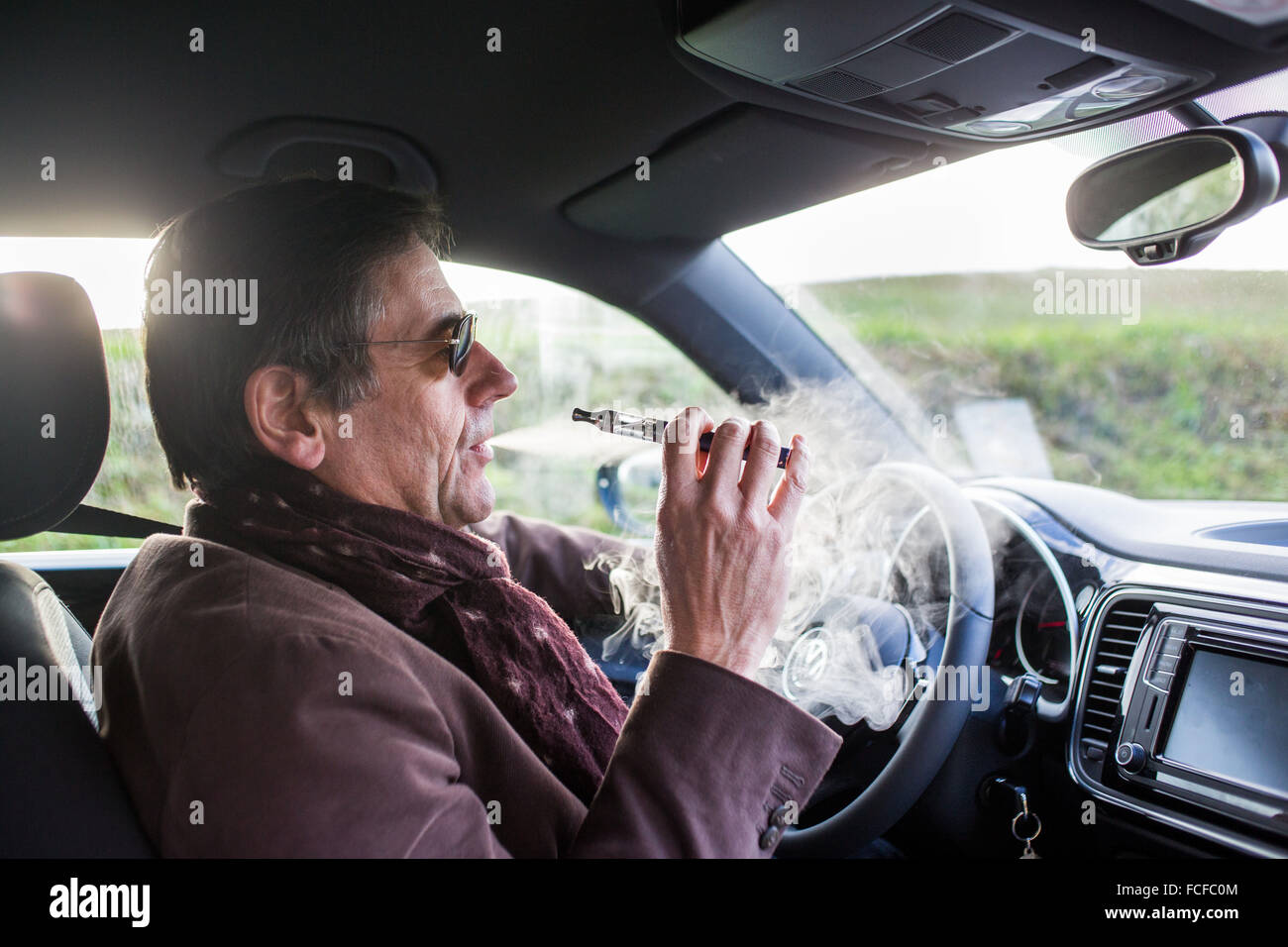 El hombre fumar cigarrillos electrónicos mientras drivingv Foto de stock