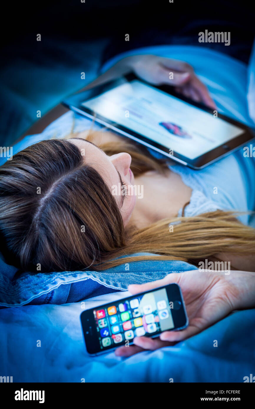Mujer utilizando una tableta digital y teléfono en la noche. Foto de stock