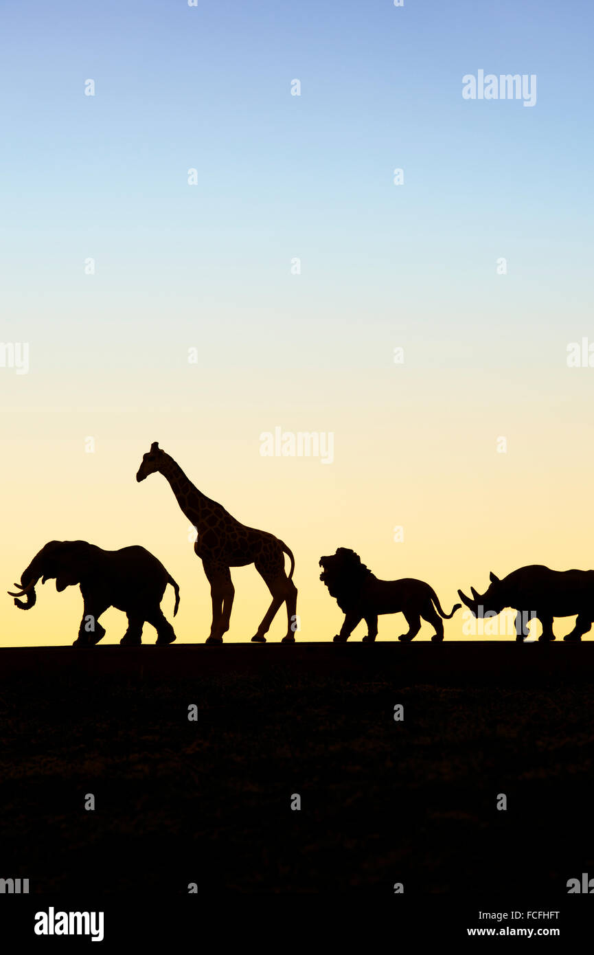 Modelos animales de juguete silueta contra un cielo amanecer Foto de stock