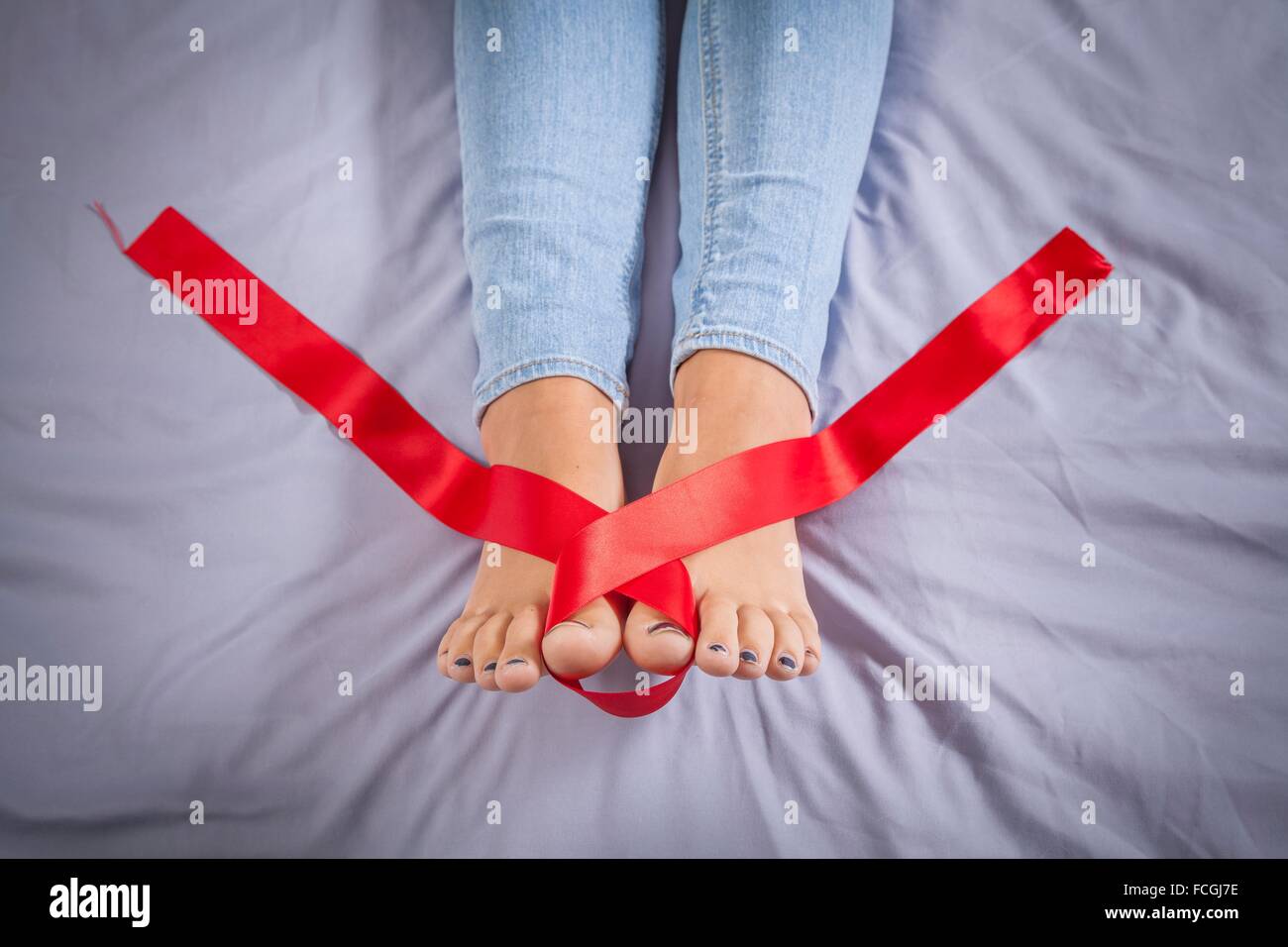 Cinta roja en los pies de una adolescente en su cama Fotografía de stock -  Alamy