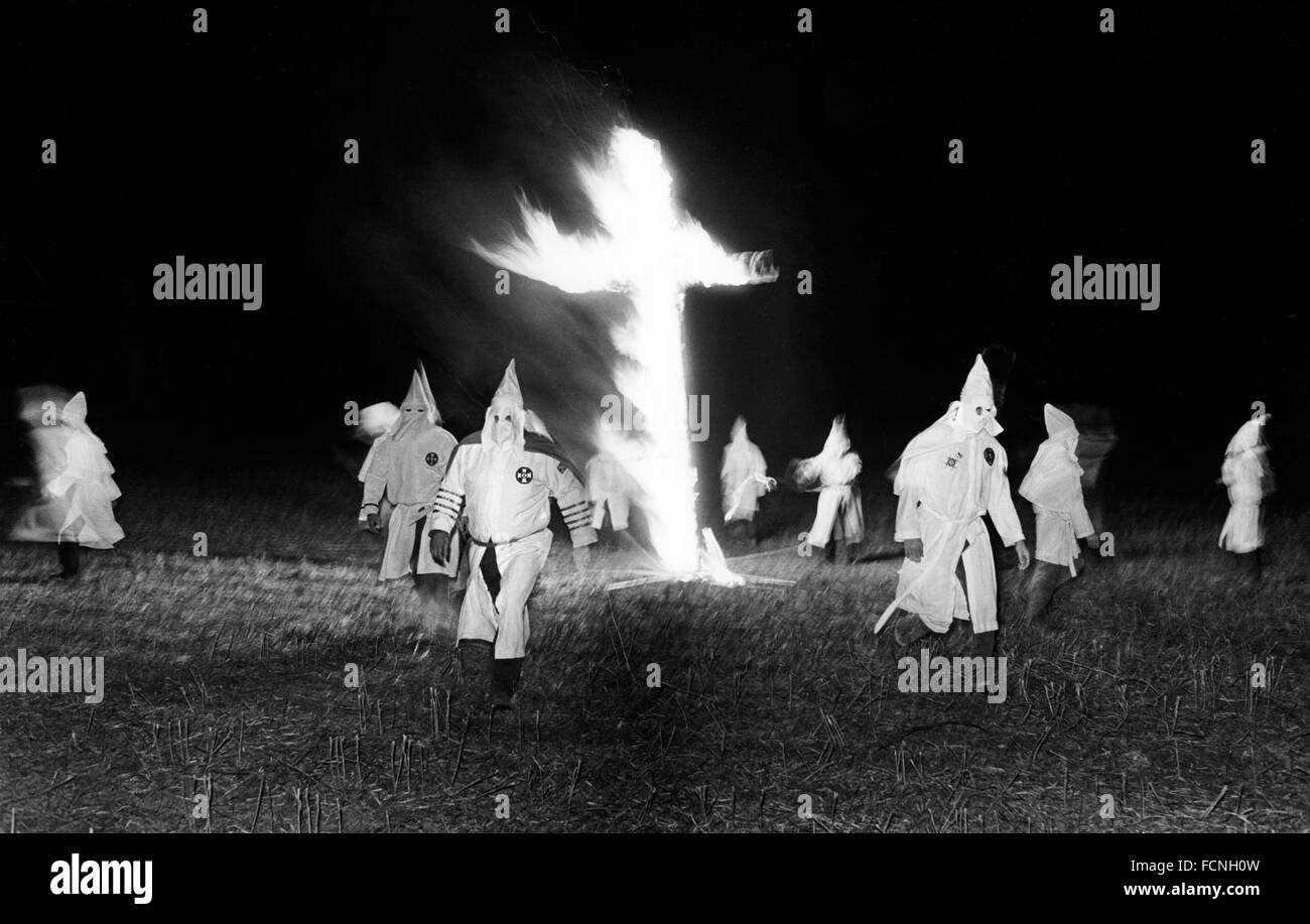 Túnica Klansmen en una cruz ardiendo en el Ku Klux Klan Rally en una granja meadow en Macon, Georgia Foto de stock