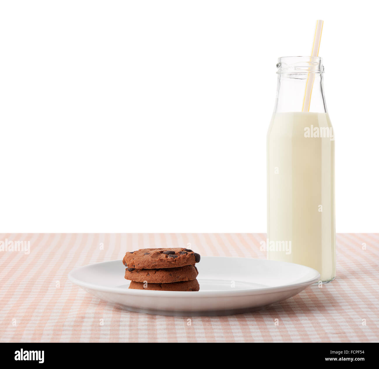 Una pila de tres galletas con trocitos de chocolate caseras en placa de cerámica blanca y una botella de leche con paja Foto de stock