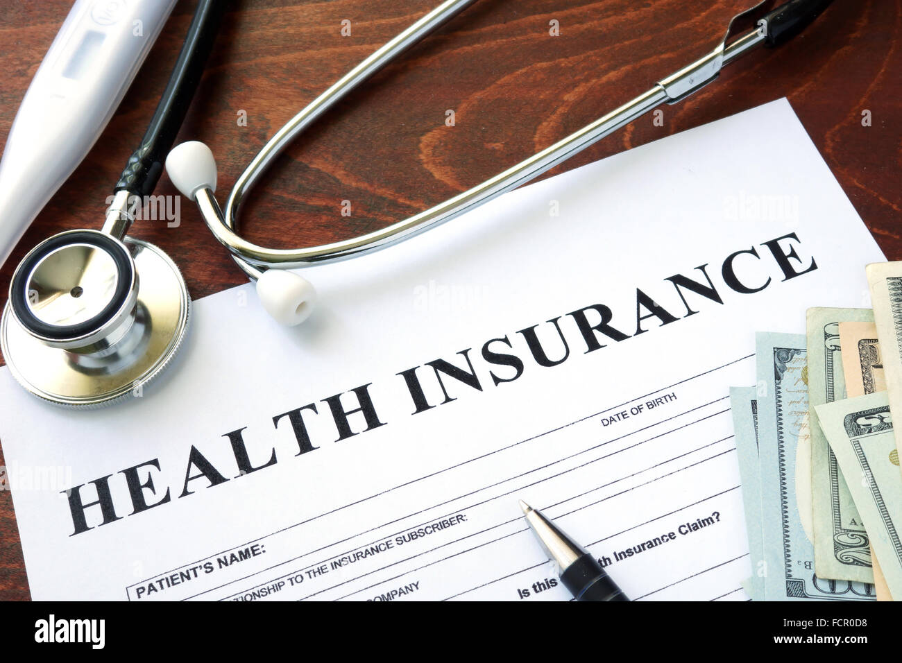 Formulario de seguro de salud y dólares sobre la mesa. Foto de stock
