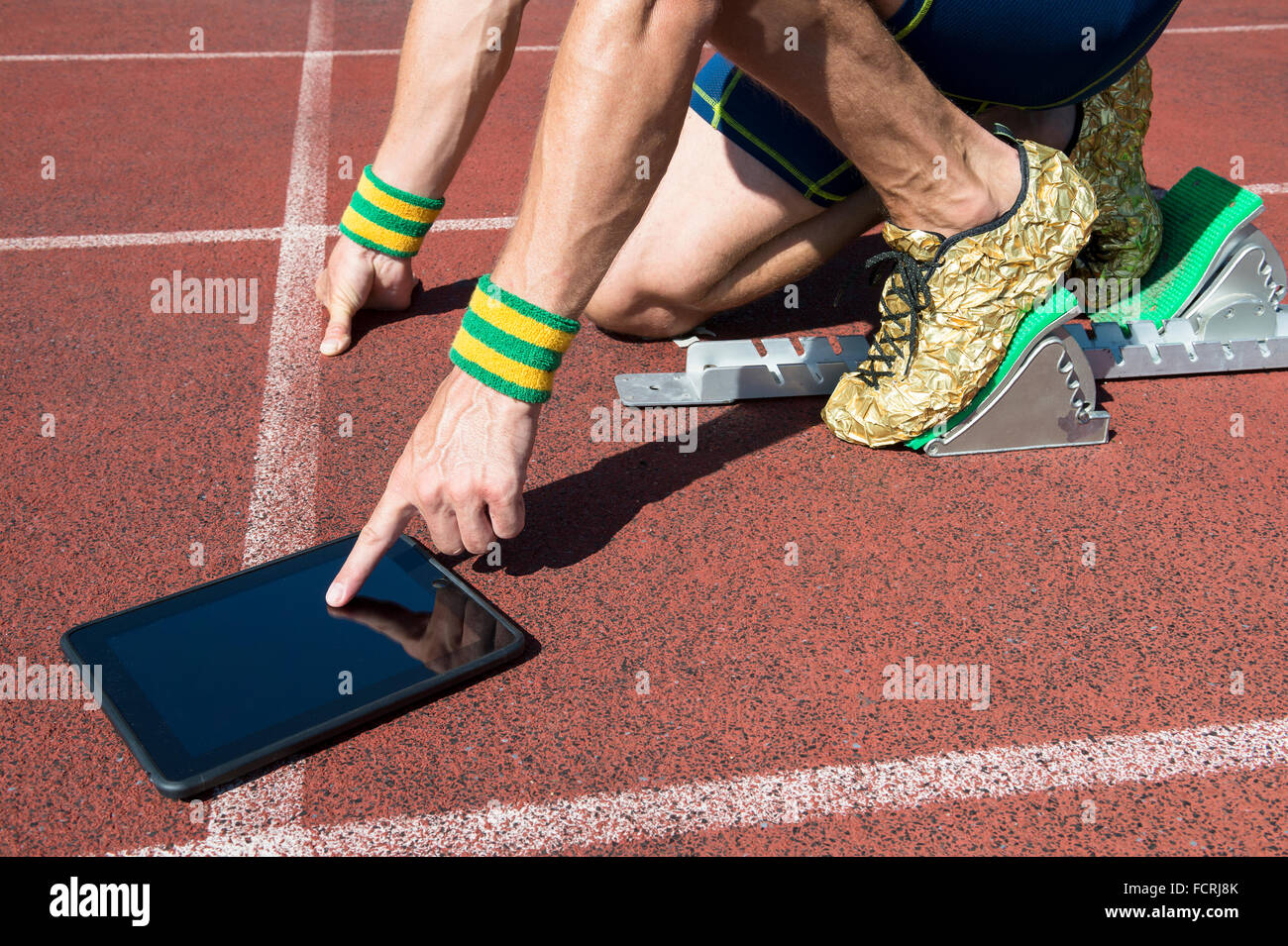 Atleta de oro zapatos para correr en en la línea de partida de una pista de atletismo llevar pulseras de colores de con tableT Fotografía de stock