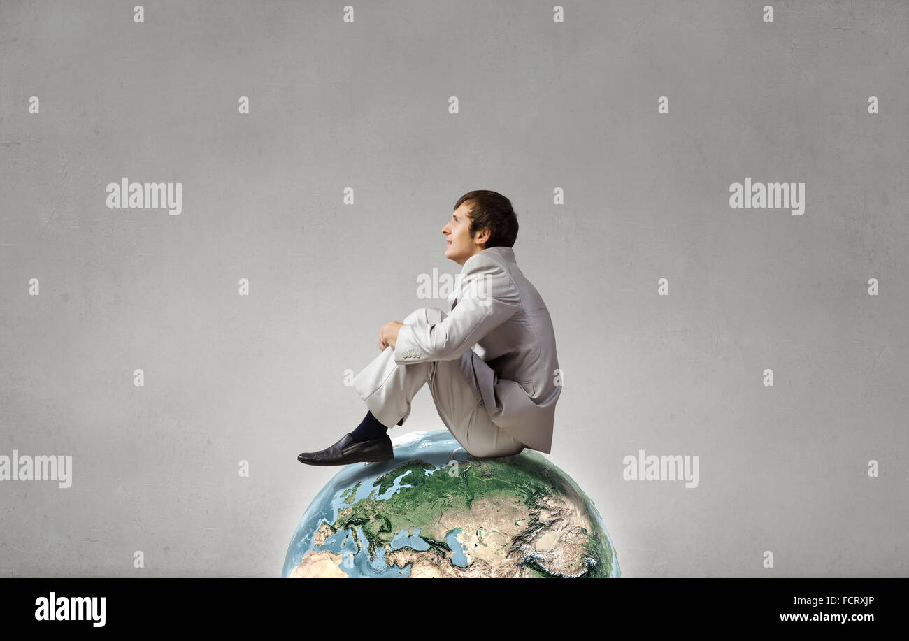 Empresario joven sentado sobre el planeta Tierra. Los elementos de esta imagen están amuebladas por la NASA. Foto de stock