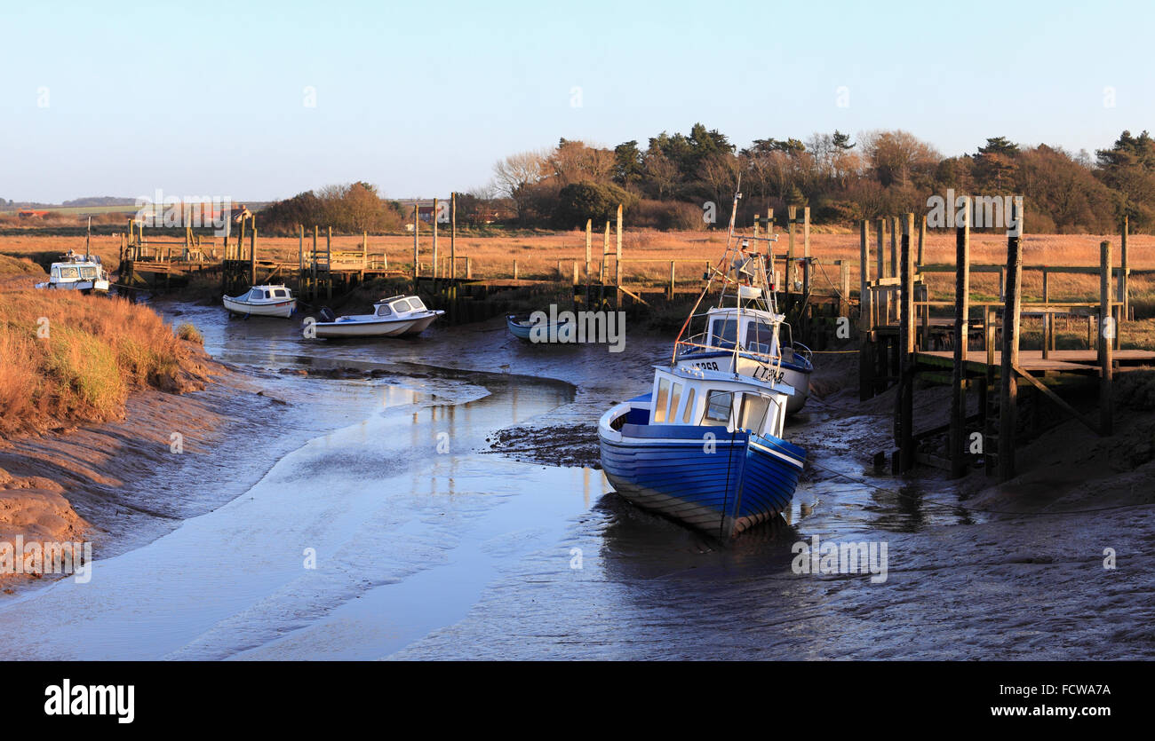 Botes y embarcaderos en marea baja en Thornham Harbour en el norte de la costa de Norfolk. Foto de stock