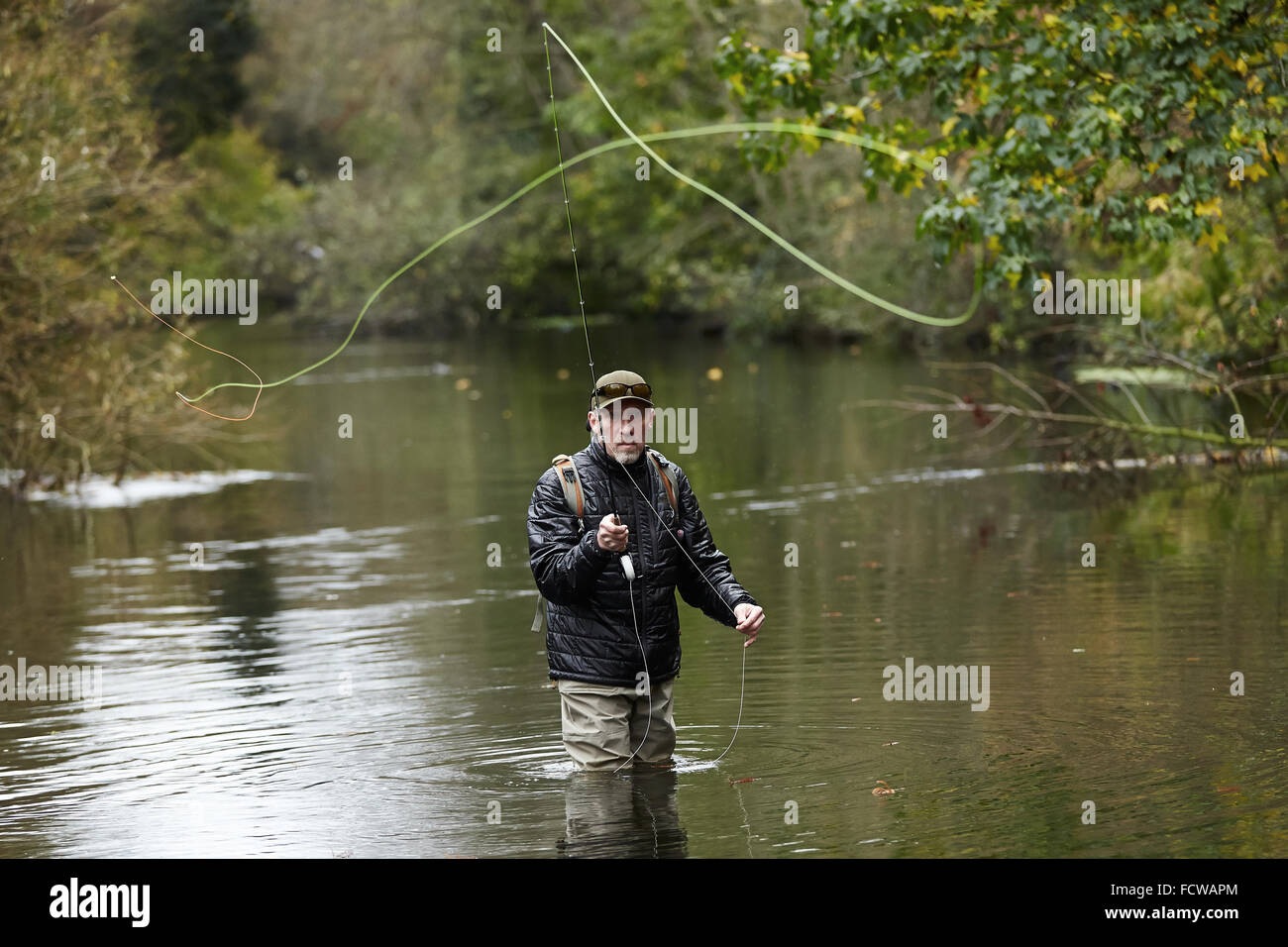 Un hombre pesca con mosca en un río Foto de stock