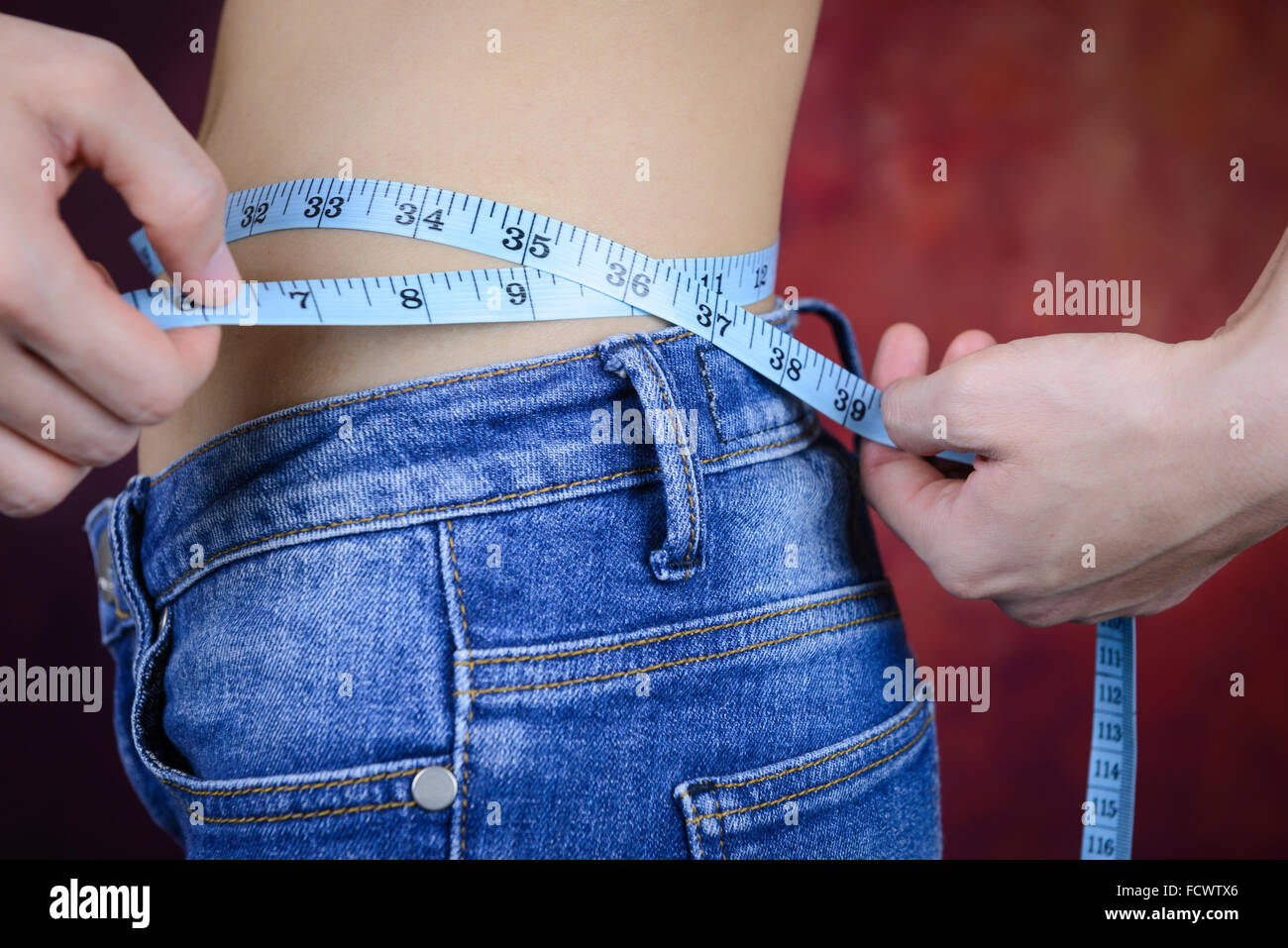 Slim mujer asiática , pantalones vaqueros, midiendo su forma corporal, cintura, nalgas Foto de stock