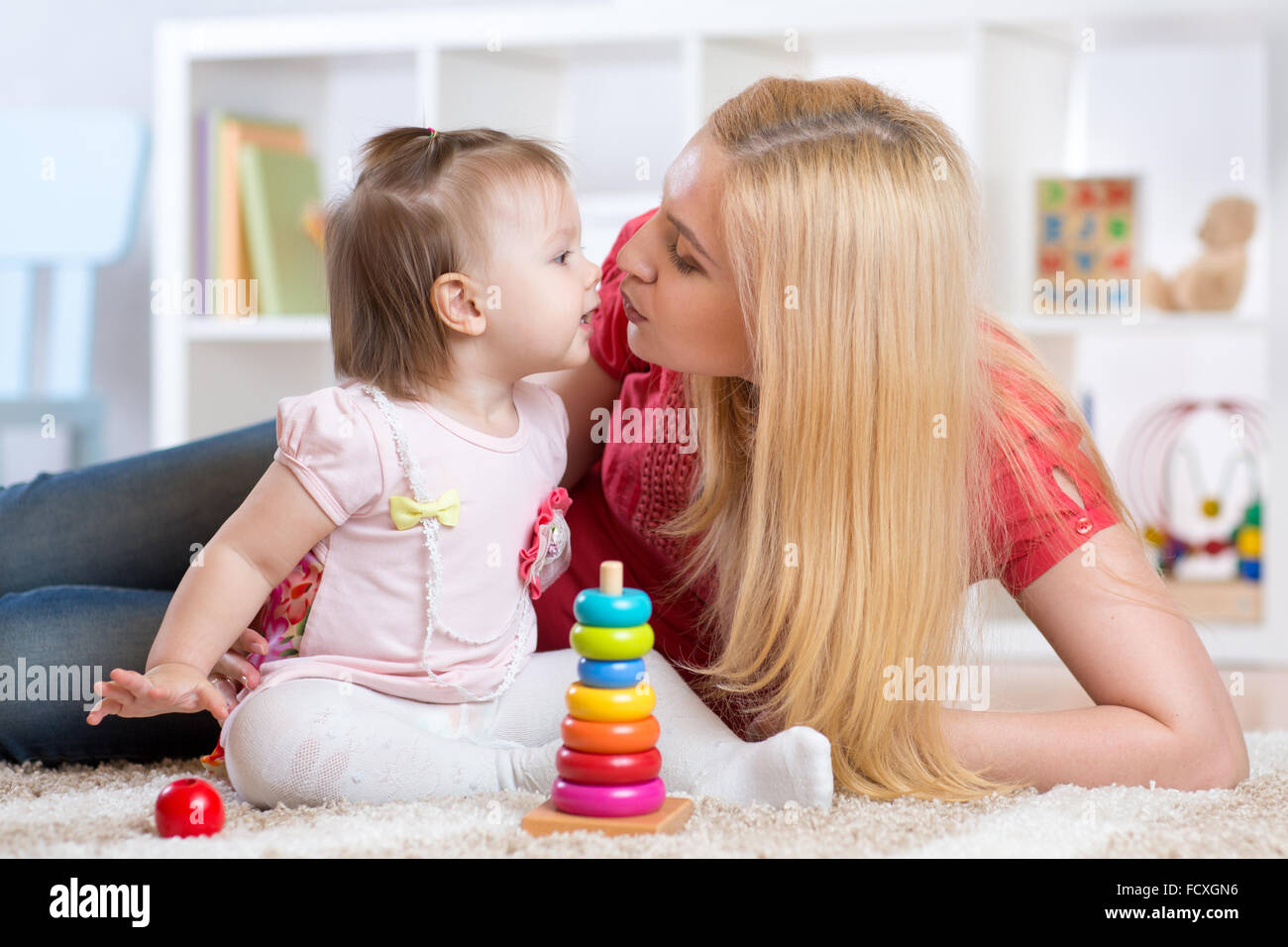 Madre e hija adentro jugando y sonriendo Foto de stock