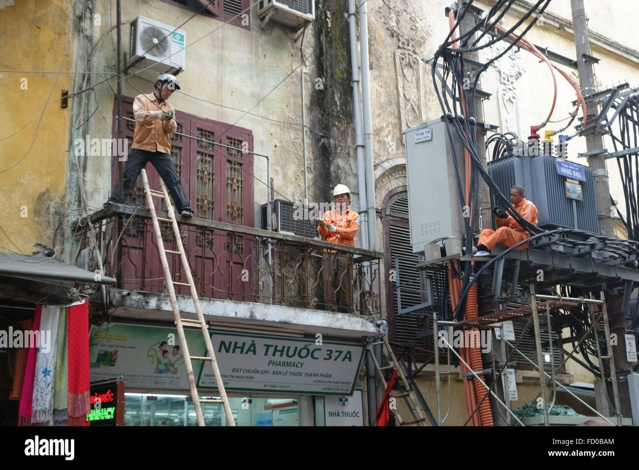 Los electricistas trabajan en cables y una subestación en la calle sin el equipo de seguridad en Hanoi, Vietnam Foto de stock